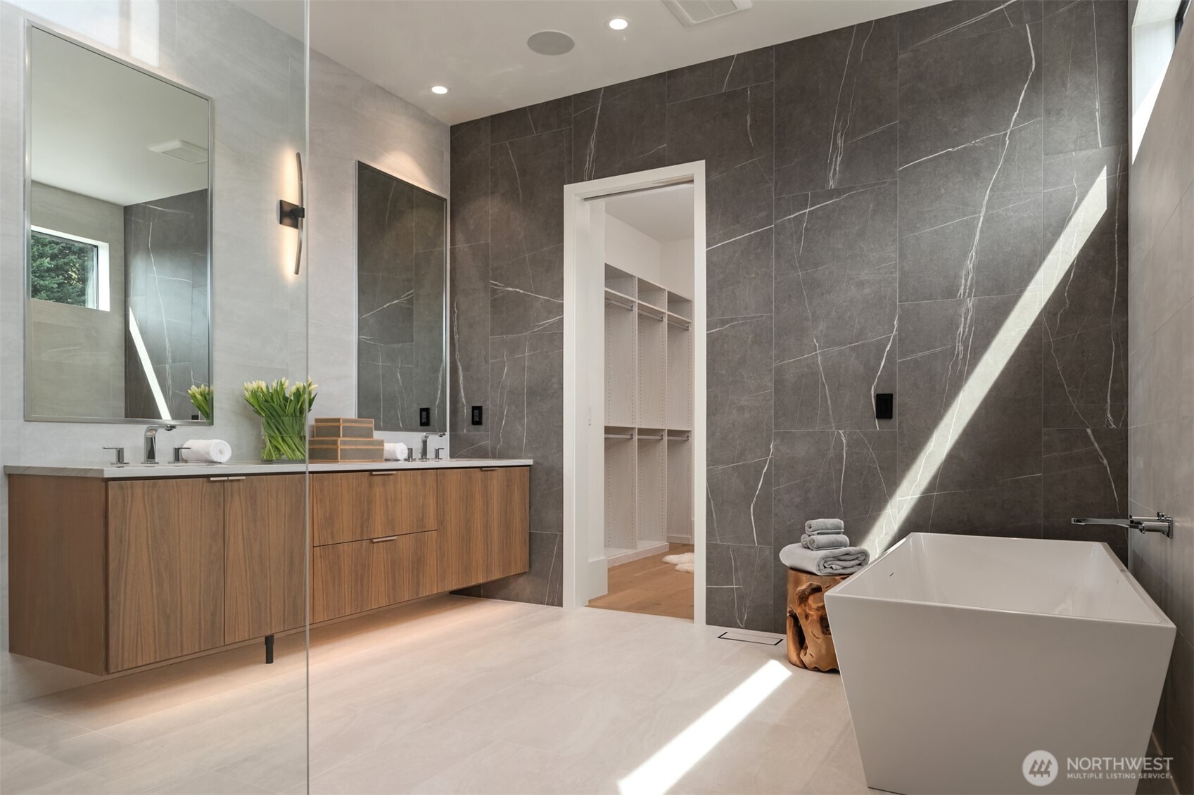 Spa-inspired primary bath with floating dual vanity, freestanding soaking tub, and sleek walk-in shower with designer tile.