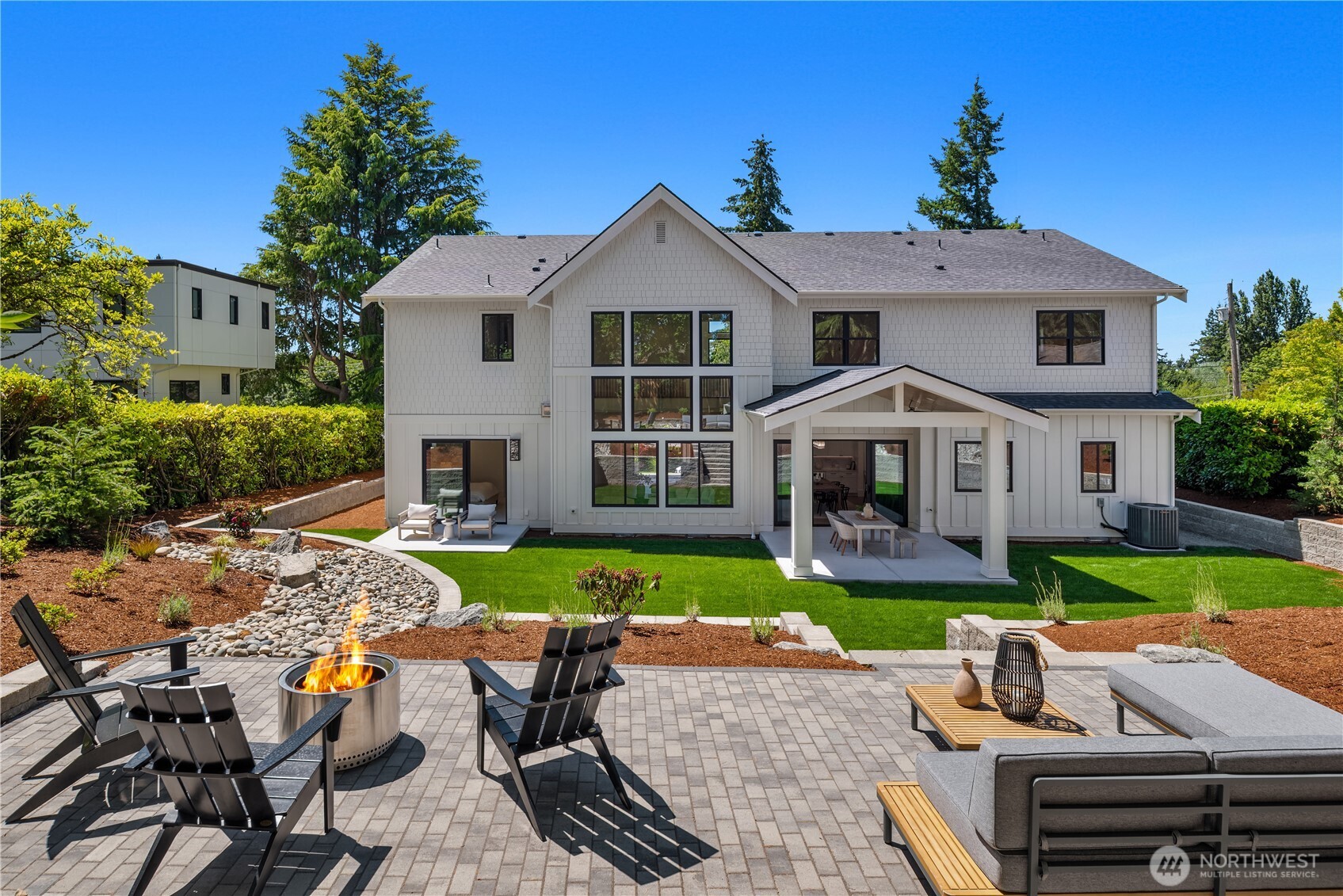 Backyard oasis with cozy firepit, lush lawn, and covered patio for entertaining