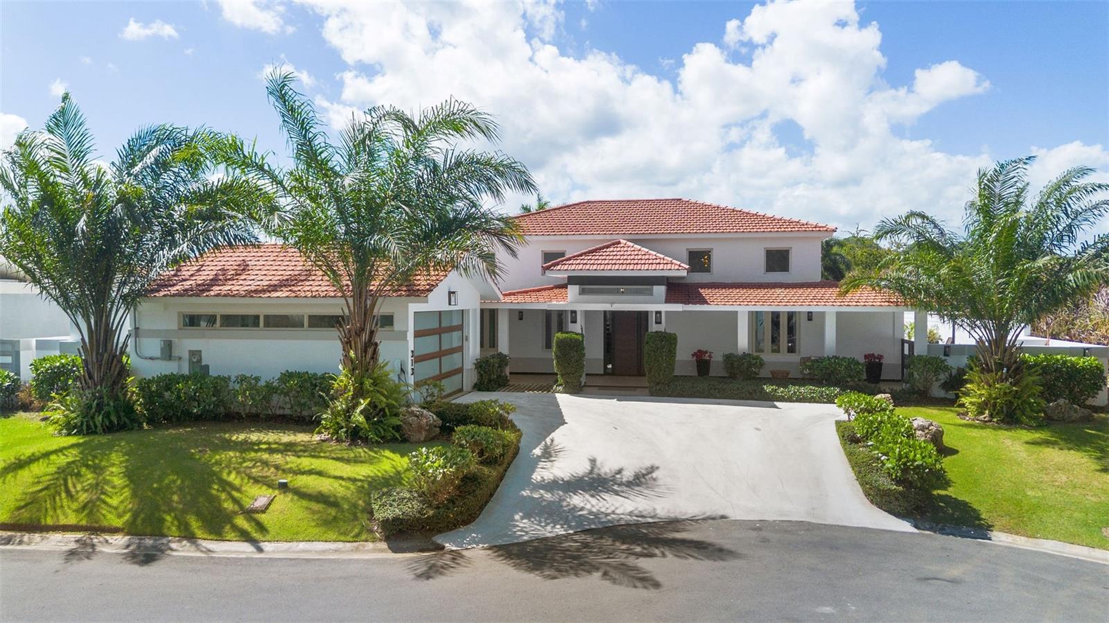 Casona Carbia model home is located on a private corner lot within a quiet cul-de-sac in the community of Sabanera Dorado. This fully remodeled contemporary residence blends modern design, comfort, and exceptional outdoor living.The home offers 6,086 total square feet, including 4,415 square feet of interior living space, and sits on a generous 1,027.67 square meter lot. The thoughtfully designed layout features four spacious ensuite bedrooms with five and a half bathrooms, providing comfort and privacy for both family and guests.Upon entering, the home welcomes you with a dramatic double-height living room, sleek architectural staircase, and abundant natural light that highlights the modern finishes throughout. The open layout connects seamlessly with the dining and kitchen areas, creating an elegant yet comfortable living environment ideal for everyday living and entertaining.The outdoor spaces are designed as a true private resort-style retreat. Expansive covered terraces provide multiple seating areas and a fully equipped outdoor BBQ kitchen, complemented by a bar and TV entertainment area overlooking the saltwater swimming pool with heater. The beautifully designed patio also features low-maintenance landscaping with artificial turf and a fun mini-golf putting area, perfect for gatherings and family enjoyment.This home is also equipped with extensive energy efficiency and resilience upgrades, including 72 solar panels, three battery backup systems, a 20 kW power generator, a 600-gallon water cistern, two water softeners, and a salt-based water system.The property includes a 2020 four-passenger golf cart, ideal for enjoying the amenities and lifestyle within the Sabanera community.This exceptional residence combines modern architecture, high-end upgrades, and a prime cul-de-sac location, offering privacy and comfort in one of Dorado’s most sought-after communities.