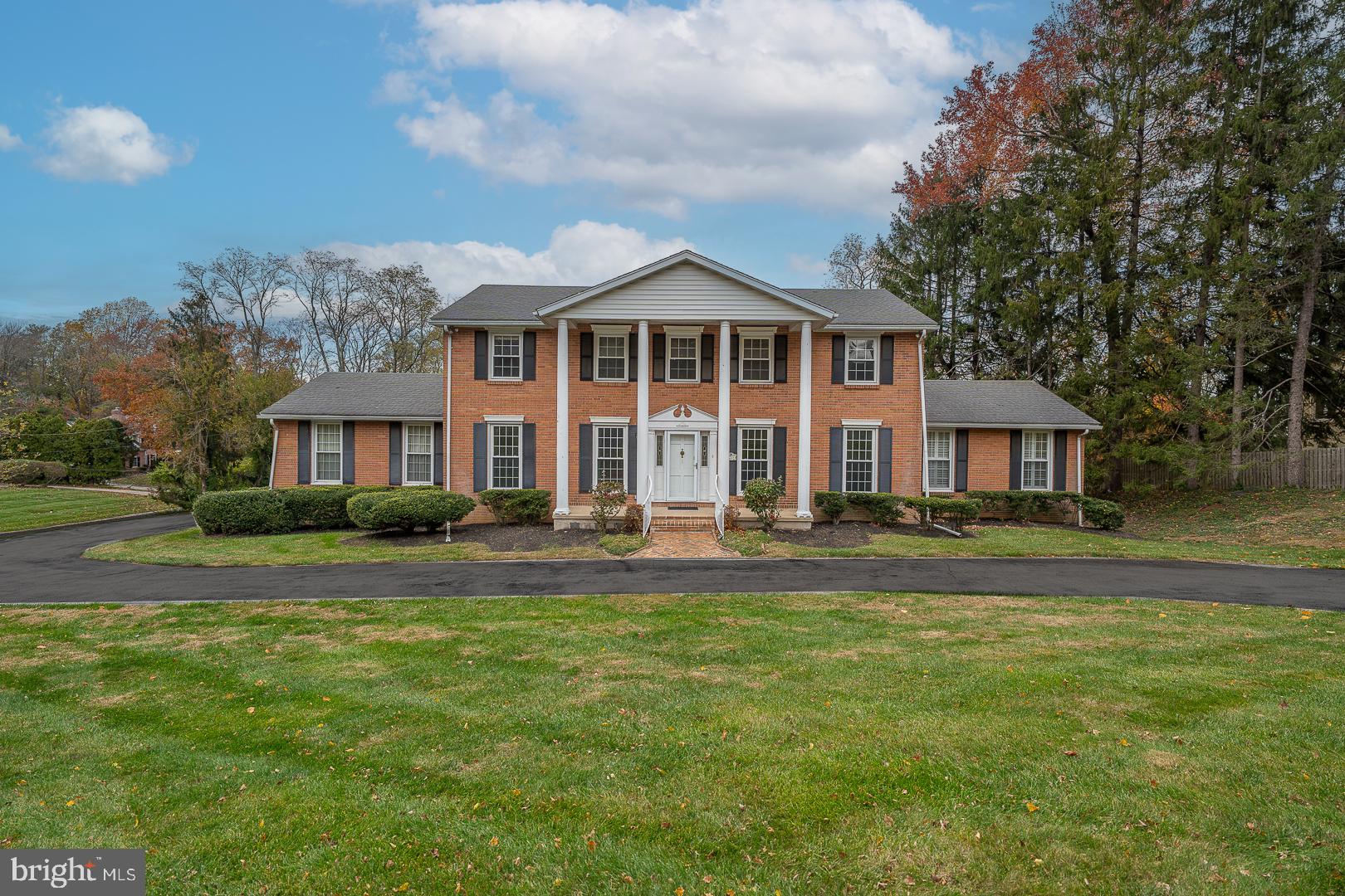 Welcome to this stately and spacious residence nestled on a beautifully landscaped 0.83-acre lot in one of Gladwyne’s most desirable neighborhoods. Offering 6 bedrooms, 4 full bathrooms, and 1 half bathroom, this home combines classic charm with modern comfort in the award-winning Lower Merion School District. A circular driveway leads to the stately front entrance, framed by timeless two-story pillars. The center hall opens to a grand formal living room featuring detailed crown molding and a double-sided gas fireplace, which also warms the covered rear porch—perfect for relaxing or entertaining. The sun-filled formal dining room with hardwood floors and built-in cabinetry sits conveniently adjacent to the kitchen for seamless entertaining. The kitchen boasts stainless steel appliances, a breakfast bar, and opens to a bright family/sunroom enhanced by skylights and sliding glass doors overlooking the tranquil backyard. The main-floor primary suite features a spacious walk-in closet with laundry and a full ensuite bath. Upstairs, a second primary suite includes its own walk-in closet and private bathroom. Three additional bedrooms with generous closets and a full hall bath with laundry complete the upper level. The finished walkout lower level offers additional living space, including a bedroom with ensuite bath and walk-in closet—ideal for guests or an au pair suite—along with a large recreation room with gas fireplace and access to the back patio and yard. Additional highlights include an oversized two-car garage, lush landscaping, and an unbeatable location close to the Philadelphia Country Club, major roadways, and all the dining and shopping in Gladwyne and nearby Conshohocken.