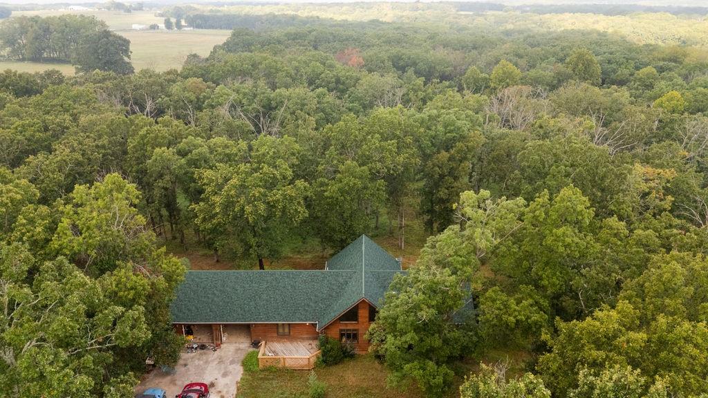Nestled in the mature timber and rolling hills of Saint Clair County sits this custom log home on 18 +/- acres. Step into peace and serenity with your own private pond, large outbuildings, and plenty of room to roam. The home is a spacious log home with vaulted ceilings, hardwood floors, and large windows that allow in buckets of natural light. The ground floor has 3 bedrooms, 2 full bathrooms, and a large living room with vaulted ceilings. An oversized back deck is accessible through the kitchen and is a PERFECT spot to watch wildlife while sipping on hot coffee in the morning. The walkout basement is finished with a bedroom, a full bath, and a large living area. An unfinished garage is also part of the basement, which provides enough space to park a UTV, zero-turn mower, or just extra storage out of the elements. A large two-car garage on the ground floor provides ample space to keep your vehicles warm, dry, and ready to go even in the coldest of weather.The large shop has concrete floors and electricity with more than enough room for projects, storage, or even a place to host large events. A horse barn with multiple stalls and tack room is a great addition for anyone with horses or other livestock needing a place out of the elements. The wooded areas surrounding the house are full of mature oak, walnut, and hickory trees. Deer and turkey travel through this area and can be viewed visiting the pond from the large deck. If you have been looking for a peaceful home, spacious getaway, or somewhere to retire, this is the place for you.