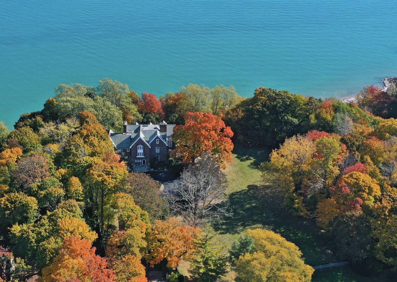 Rare opportunity to own this beautiful lakefront home on almost 4 acres w/ 300' of Lake Michigan shoreline on coveted Mayflower Road. Located down a tree-lined driveway at the end of a private lane, this stately brick home was built in 1914 and features 7 bedrooms, 6.1 bathrooms, 6 fireplaces, original millwork, high ceilings, a gourmet kitchen, an elevator, a newer slate roof, and wonderful vintage details throughout. On the 1st floor, you'll find a large library w/ built-in shelving, a wood-burning fireplace, beautiful trim & millwork, and wonderful character. The family room overlooks Lake Michigan and contains three walls of floor to ceiling windows allowing for amazing views all year long.  The spacious kitchen features commercial grade appliances, a Butler's Pantry, Storage Pantry, an island, and plenty of storage & prep space. On the 2nd floor, the large Primary Suite contains a bedroom w/ wood-burning fireplace and views of the lake, a huge dressing room w/ abundant closet space, built-in dressers, vanity table, & shelving and a spacious primary bathroom with a separate tub, shower and commode room. Three additional bedrooms, an office, a meditation room, a large linen room, and a sitting room that contains the elevator complete this level.  The 3rd floor has 3 large bedrooms, 2 full bathrooms, and a game room.  The unfinished basement has lots of dry storage space and can be finished out to create even more wonderful amenities (theater room, wine cellar, play space, etc.).  Outside, the expansive side yard is perfect for outdoor entertaining, games, or special events. Two stone terraces provide additional space for entertaining and enjoying the stunning scenery. A stone staircase w/ handrail leads down to the lake while passing through a lovely gazebo w/ seating down by the beach. This beautiful home also has a slate roof (2003) newer mechanicals, and professional landscaping.  Don't miss this opportunity to enjoy lakefront living in this amazing private setting w/ an incredible beachfront!