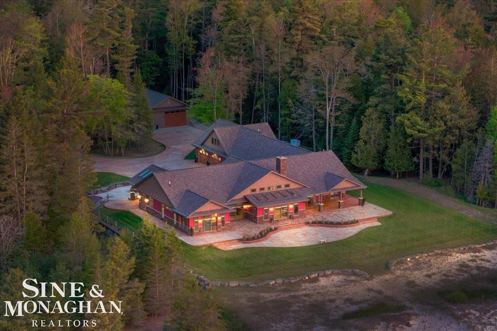 Welcome to 950 N Lake Huron Shores Drive, a rare and extraordinary custom lakefront estate offering 6750 sq. ft. of refined rustic elegance; on 10 wooded acres with 250 feet of private Lake Huron frontage. This 4-bedroom, 4.5-bath ranch home showcases exceptional craftsmanship with reclaimed wood details, birch floors, and Michigan blue pine throughout. Designed for both comfort and sustainability, the home features geothermal heating, an ERV air system, dual septic tanks, and a whole-house Generac generator. The gourmet kitchen is equipped with Bosch and JennAir appliances, hickory cabinets, a cooktop, and beach glass exposed concrete countertops, while natural light floods the open-concept living space through Pella windows, heavy-duty sliders, transoms, and a dramatic 2-story fireplace. The private master wing includes a sunroom, jetted tub, oversized shower with high end plumbing fixtures, and expansive walk-in closet. Additional highlights include a guest wing with mini kitchenette and living area, As well as a completely finished flex space with full bathroom and control room over the garage. Not to mention the upgraded exterior such a custom stained concrete wrap around patios, fire pit, dog wash, outdoor shower, and commercial-grade grill area.  A 3.5-car finished garage with workspace, epoxy floors  and utility sink. A 30x50 heated & cooled pole barn with additional workshop, bathroom, loft, and lean-to for unlimited storage potential and work space. The beautifully landscaped property features a creek, unparalleled beach access, 650 feet of private trails, and the convenience of biking distance to downtown and the Harrisville Harbor. With smart home technology, remote HVAC and security access, expansive sandy beachfront, and panoramic lake views from every room, this energy-efficient home redefines luxury waterfront living in Northern Michigan.