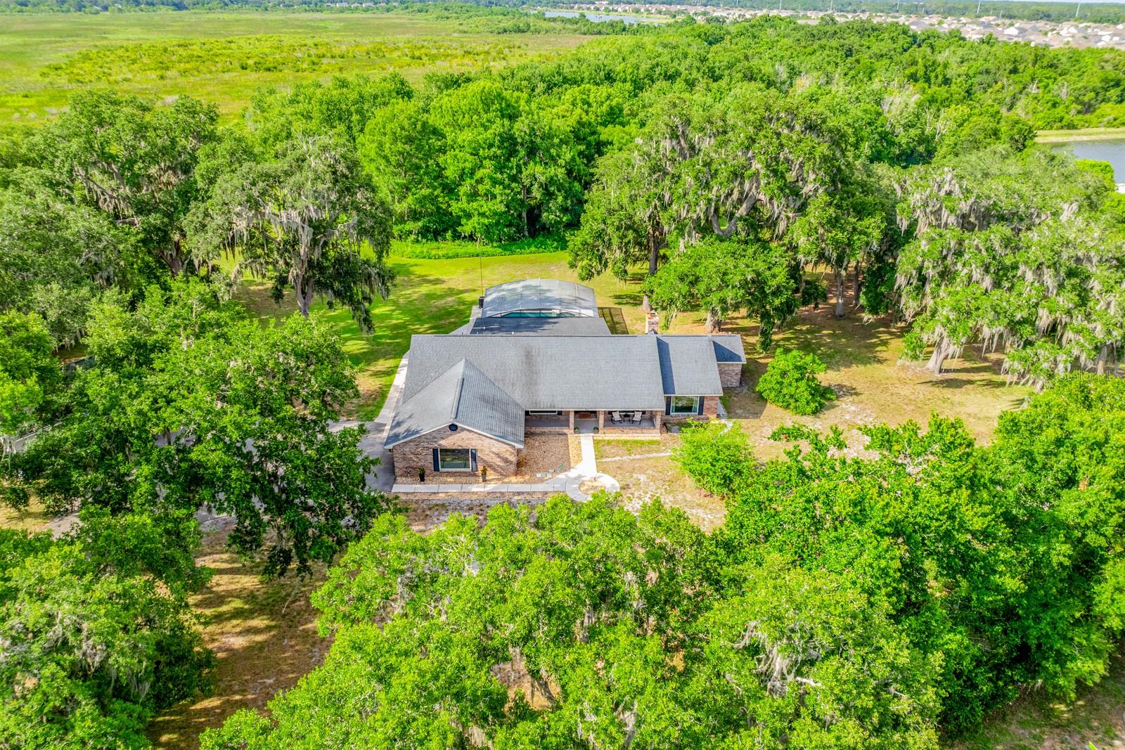 Virtually Staged. Seller may consider buyer concessions if made in an offer ~ Peaceful, private, and packed with possibilities, this beautifully updated POOL HOME sits on TWO PARCELS totaling 5 ACRES with a PRIVATE GATED ENTRANCE, a 3/4 ACRE POND WITH DOCK, and beautiful views of Lake Runnymede! Recent upgrades include a Rheem intelligent WATER HEATER (2026), Fleck AIO WATER FILTRATION/SOFTENING SYSTEM (2026), refreshed third bath (2026), updated laundry room (2026), painted pool deck and patio (2026), CEDAR TONGUE & GROOVE FRONT PORCH CEILING (2026), hurricane-impact DOUBLE PANE WINDOWS (2025), FRESH INTERIOR & EXTERIOR PAINT (2025), a beautifully remodeled primary bath (2025), and LUXURY VINYL PLANK FLOORING THROUGHOUT (2023/2026). The high-efficiency 5-ton, 18-SEER A/C was installed (2024), and the roof is approximately 7 years old. Designed for both everyday living and entertaining family and friends, the OPEN CONCEPT floor plan offers flexible spaces, including a BONUS ROOM/4TH BEDROOM with potential for an in-law suite and a FLEX/OFFICE that could easily become a 5th bedroom. The chef's GOURMET KITCHEN anchors the interior, paired with a light and bright living space that boasts a WOOD BURNING FIREPLACE built into a brick feature wall, while an OUTDOOR ELECTRIC FIREPLACE creates the perfect gathering space to relax and unwind. Be sure to explore the spacious PRIMARY SUITE, ideally situated on its own wing with a picture window that lets the light pour in, a huge UPGRADED EN-SUITE BATH that feels like stepping into a spa and the perfect complement of a large WALK-IN CLOSET complete with custom storage. The detached 32x42 GARAGE/WORKSHOP features 12-foot ceilings and AT&T Fiber, making it ideal for hobbies, storage, business use, or future expansion. Outside, enjoy total privacy with mature trees, sprawling green space, banana, guava, rose apple, elderberry, blackberry, avocado trees, and pineapple plants. With AT&T Fiber Internet, Starlink capability, NO HOA, seller financing available, and unlimited potential for large gatherings, recreation, or multi-generational living, this one-of-a-kind property feels worlds away while remaining just 20 minutes from Lake Nona and convenient to TOP-RATED SCHOOLS, shopping, dining, parks, major roadways, and Central Florida attractions. ** 5 ACRES ** PRIVATE POND ** LAKE VIEWS ** ENDLESS POSSIBILITIES ** Welcome to the lifestyle you have been searching for in St. Cloud ~ and WELCOME HOME!