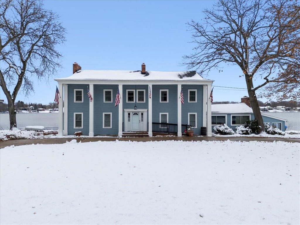 Welcome to a Brighton lakefront setting that instantly pulls you in. With 160 feet of shoreline stretching out in front of you, the view feels wide open and peaceful from the moment you arrive. Step onto the large deck and you can picture slow mornings, long summer dinners, and a front row seat to everything happening on the water. It is the kind of space that naturally becomes the heart of everyday living.Inside, the home offers the comfort and flexibility you want in a true year round retreat. Five well sized bedrooms and three and a half baths give everyone room to spread out, host guests, or set up extra space for work or hobbies. A private dining room keeps gatherings simple, while the open living areas stay connected and easy to use throughout the day.The oversized garage adds another layer of convenience with storage for vehicles, lake gear, and a workshop area ready for projects. A circle driveway makes arrivals and parking simple, especially when friends stop by.