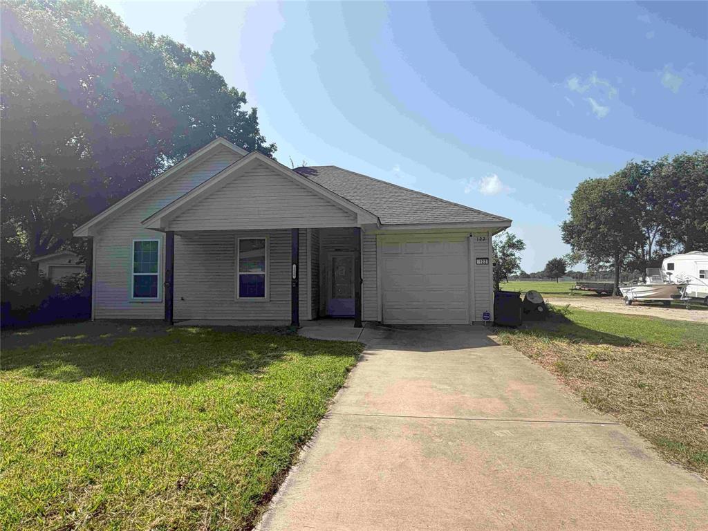 Single-story residence featuring light-colored siding, a covered front porch, and an attached garage with a white door