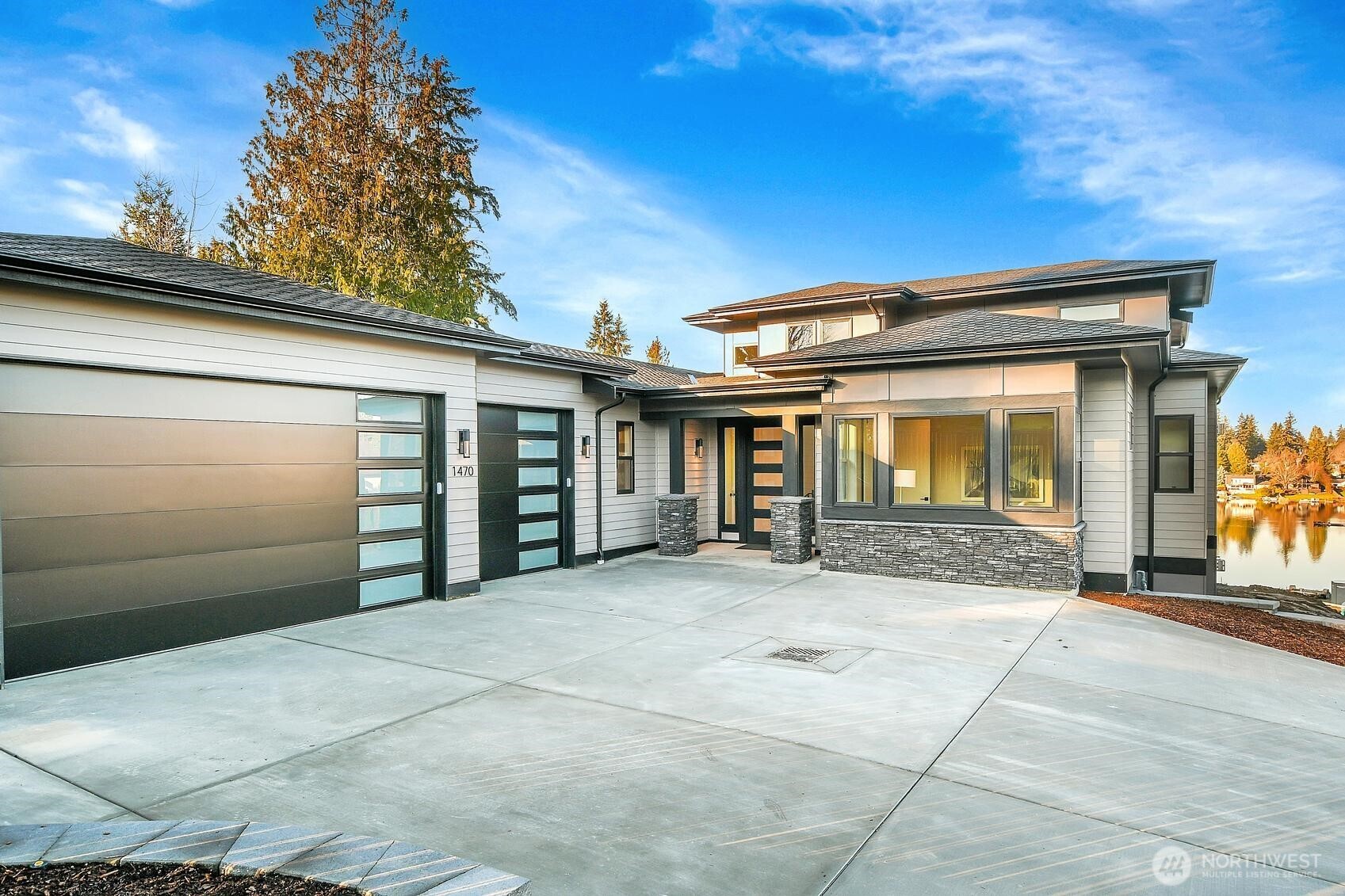 Rare opportunity to own a NEW Northwest Contemporary masterpiece with elevated lake and territorial views of Lake Burien. Located in a private, gated enclave of 4 custom homes, enjoy swimming, paddle boarding and fishing via shared easement access to the 44-acre private lake.  Spanning 4,492 sq ft of modern living, the home features soaring 16’ ceilings, expansive windows and a design for grand entertaining. The great room boasts a sleek alabaster stone fireplace, while the dining area includes a wet bar leading to a dry Trex deck with a PNW inspired wood-lined ceiling. A chef’s gourmet kitchen is equipped with GE Café appliances, including a 6-burner range, double ovens, oversized quartz island, prep sink, walk-in pantry and coffee station.  The main-level primary suite offers a spa-inspired 5-piece bath with heated floors and walk-in closet. Also on the main: a private office (or 5th BR), junior suite, laundry/mudroom and 3-car garage with Level 2 EV charging. The lower level (w/ 10' ceilings) provides incredible flexibility for guests or multi-generational living with a 2nd primary suite (5-piece bath/walk-in closet), large living room, kitchenette, media room with wet bar/cinema lighting, gym, wine/podcast space and 4th BR. Outdoor living includes a dry covered patio with a dual-sided fireplace & hot-tub hookups (perfect after a dip in the lake). Minutes to Sea-Tac, Seattle & Tacoma. Walking distance to St. Francis School & Olde Burien. Experience luxury lakeside living!