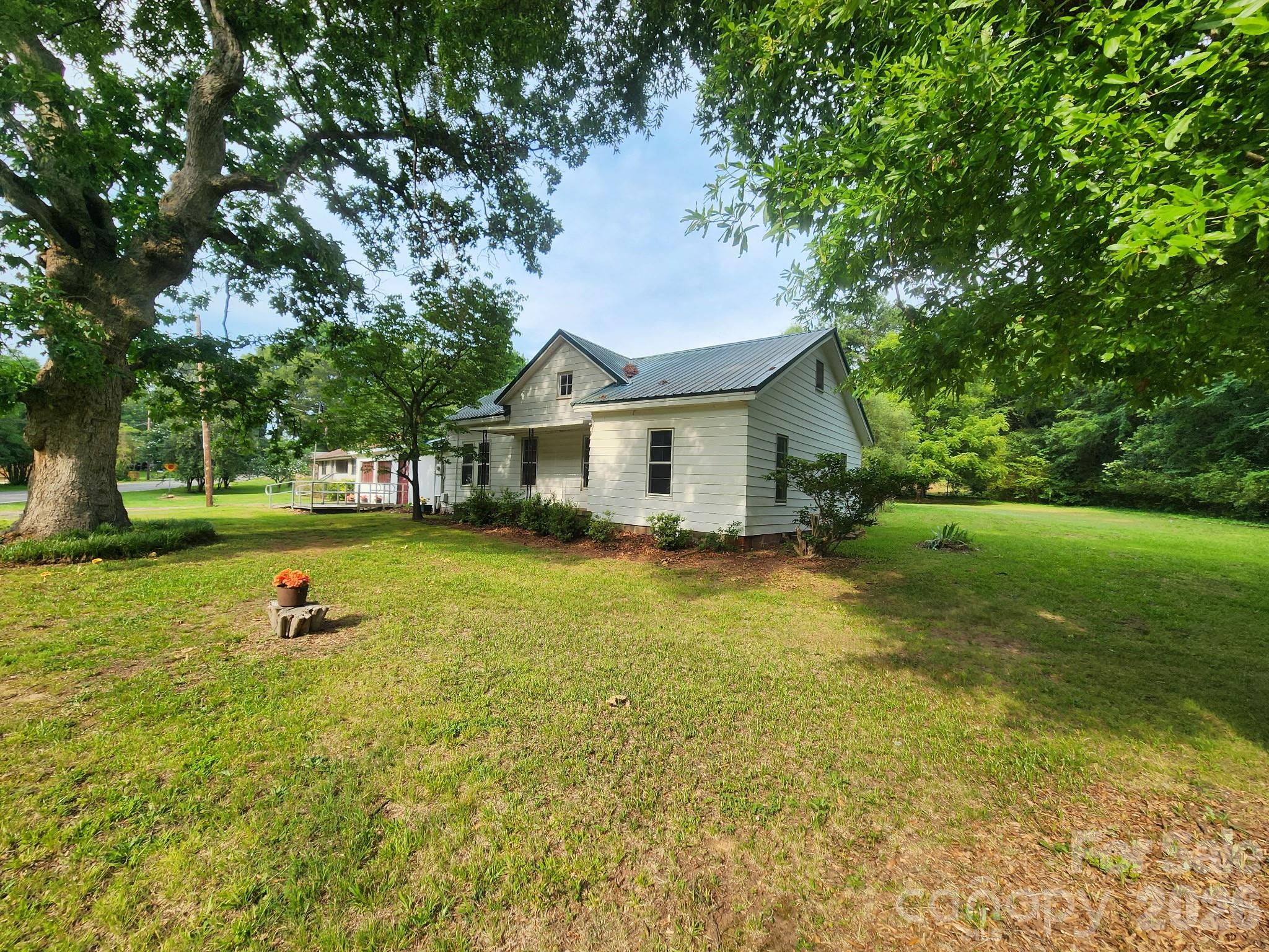 Great Location and a Home that's ready for your vision. Metal Roof in 2012, Natural Gas Heat Unit 2015. An Attached Metal Carport was made into a living space. This room has baseboard heat and a window A/C unit - No Permits were pulled. Railroad tracks are beside the property; there is an easement. Active Train per the seller; it goes by a few times a day and does blow horn. Piedmont Natural Gas Easement runs alongside and in the same direction as the railroad easement- side by side. This was an old homeplace, and the home could be renovated, but the seller will make no repairs, and the home is being sold in its as-is current condition with no representation as to the condition of the home.  This could be a great building lot if an investor wanted to tear down the home and build new. It's a Nice level lot with several trees. Zoned N1-A. Older greenhouse/ out building on the property. No permits on file, no current survey. There is an old Plat from 1914 in the attachments. Fireplace/Chimney is non-functioning; it has been covered up inside the home and is not visible from the roof; the brick Chimney can be seen in the attic. The front room (living room) at the front entry porch was used as a bedroom; this room has no framed closet.