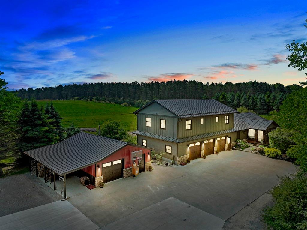 Striking two-story home showcasing a modern take on farmhouse and barn-inspired architecture. This gorgeous countryside retreat offers everything you desire and more! Nestled on 14 acres, the home features 6 bedrooms and 5 bathrooms. The main floor primary suite includes a private bath with a spacious tiled walk-in shower, makeup station, and walk-in closet. Enjoy breathtaking views from the kitchen, complete with an island boasting a butcher block countertop, quartzite surfaces, and a custom black walnut live edge bar top. The upper level offers a second kitchen with hickory floors and cabinets, three additional bedrooms (one with its own attached private bath), and a custom Amish-made bar area-perfect for entertaining guests or housing your collection. The fully finished basement provides a large family room, an additional bedroom with a shared attached bath, and a dedicated laundry/storage area. For extra convenience, the attached 3-car garage is outfitted with built-in cabinets and shelves for storage. An additional garage features a wood stove and a dog kennel room that opens to a fenced area. A massive pole barn includes a spacious stall suitable for a camper and a loft above two other stalls. Outside, enjoy a screened cedar front porch and a large back deck ideal for relaxation and entertaining. The expansive property also features a pond with a beach area, creek access, and designated sections for food plots. Upgrades listed in associated docs.