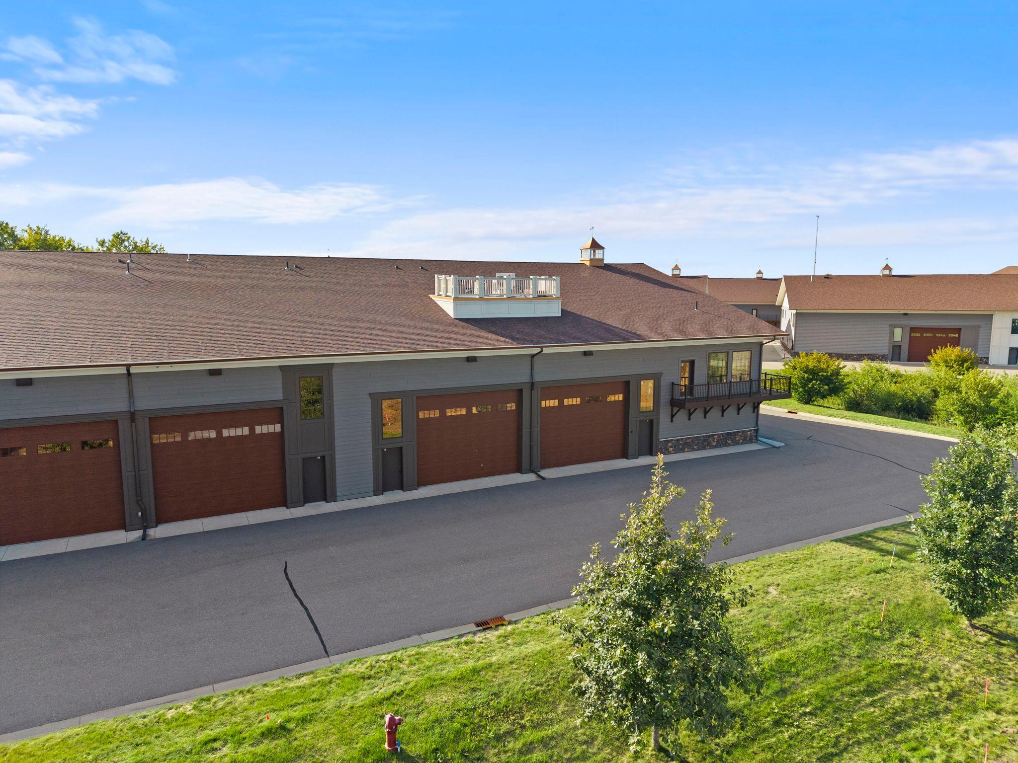 Welcome to an exceptional finished garage condo at the prestigious Medina Automotorplex, thoughtfully designed and professionally built out for the serious collector, automotive enthusiast, or hobbyist. This impressive space offers the perfect combination of functionality, security, and flexibility, whether you envision it as a private collector garage, professional-grade workshop, or one-of-a-kind automotive retreat. The impressive 30’ wide by 40’ deep main-level high-bay area features 20’ ceilings, a commercial-grade, fully insulated wood-look garage door with a myQ-compatible commercial-grade operator, Pella windows, acoustical black metal ceiling, in-floor heat with a Wi-Fi-controlled thermostat, split AC, and a large fan. A 150-amp electrical service with quad outlets throughout provides ample power, while floor drains and a hose bib make washing and maintaining vehicles easy. The lower level features epoxy floor coating, a 55” Samsung TV, ½ bath with a large utility sink, 40-gallon electric water heater, and water softener providing soft water throughout. A fire suppression system serves both levels, each room, and the attic for added peace of mind.The 30’ wide by 20’ deep loft provides an impressive extension of the space with a comfortable living room or sitting area, custom cabinetry and entertainment center, and a 75” Samsung TV. The full kitchen offers custom cabinetry, center island with breakfast bar seating, LG refrigerator, cooktop, oven, microwave, dishwasher, and a unique glass-cover backsplash. The loft also includes a ¾ bath with ceramic shower. Bath fans and the cooktop hood are vented to the exterior. Luxury Vinyl Plank flooring completes the loft. Additional features include some furnishings that are included with the sale, making this exceptional space ready to enjoy from day one. Beyond the unit itself, the Medina Automotorplex campus offers gated entry, exterior security cameras, and floodlights over each overhead door, providing an added level of security for owners. Located within the exclusive Medina Automotorplex, this is more than a place to store your vehicles—it’s a private destination designed around your passion. Whether used as a sophisticated collector garage, fully equipped workshop, or ultimate hobby space, this exceptional finished unit is ready to enjoy.