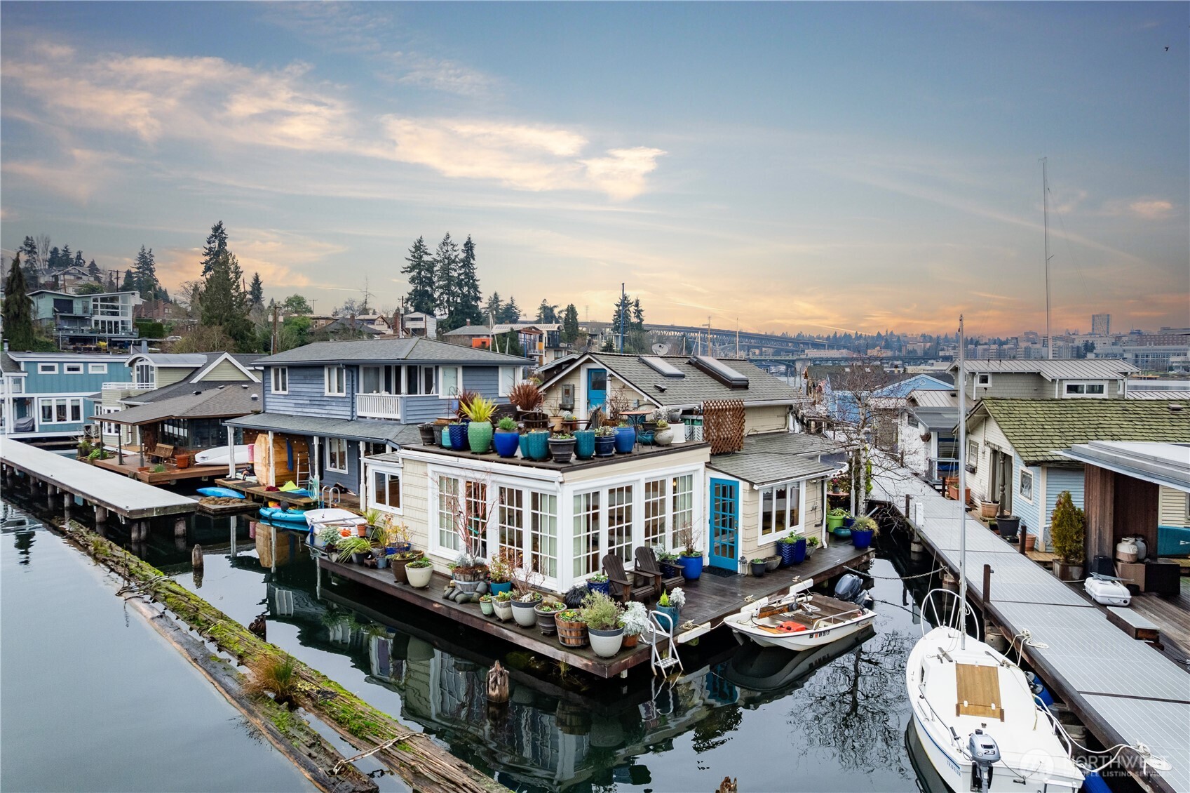 Towards the end of one of the nicer docks off the shores of Portage Bay, this serene waterfront retreat captures expansive south-facing light & breathtaking views while blending timeless character w/ thoughtful updates. Newly updated kitchen anchors main level & opens to inviting entertaining spaces that flow seamlessly to multiple decks. Large windows frame shimmering water, boats drifting by & ever-changing light throughout the day. The main floor features a spacious bedroom & full bath, while upstairs a cozy sitting area leads to a 2nd BR & rooftop deck w/ sweeping vistas toward the Cascade Mountains. Outside enjoy a private garden, room for kayaks, & ample storage on shore in exceptional Portage Bay sanctuary in the heart of the city.