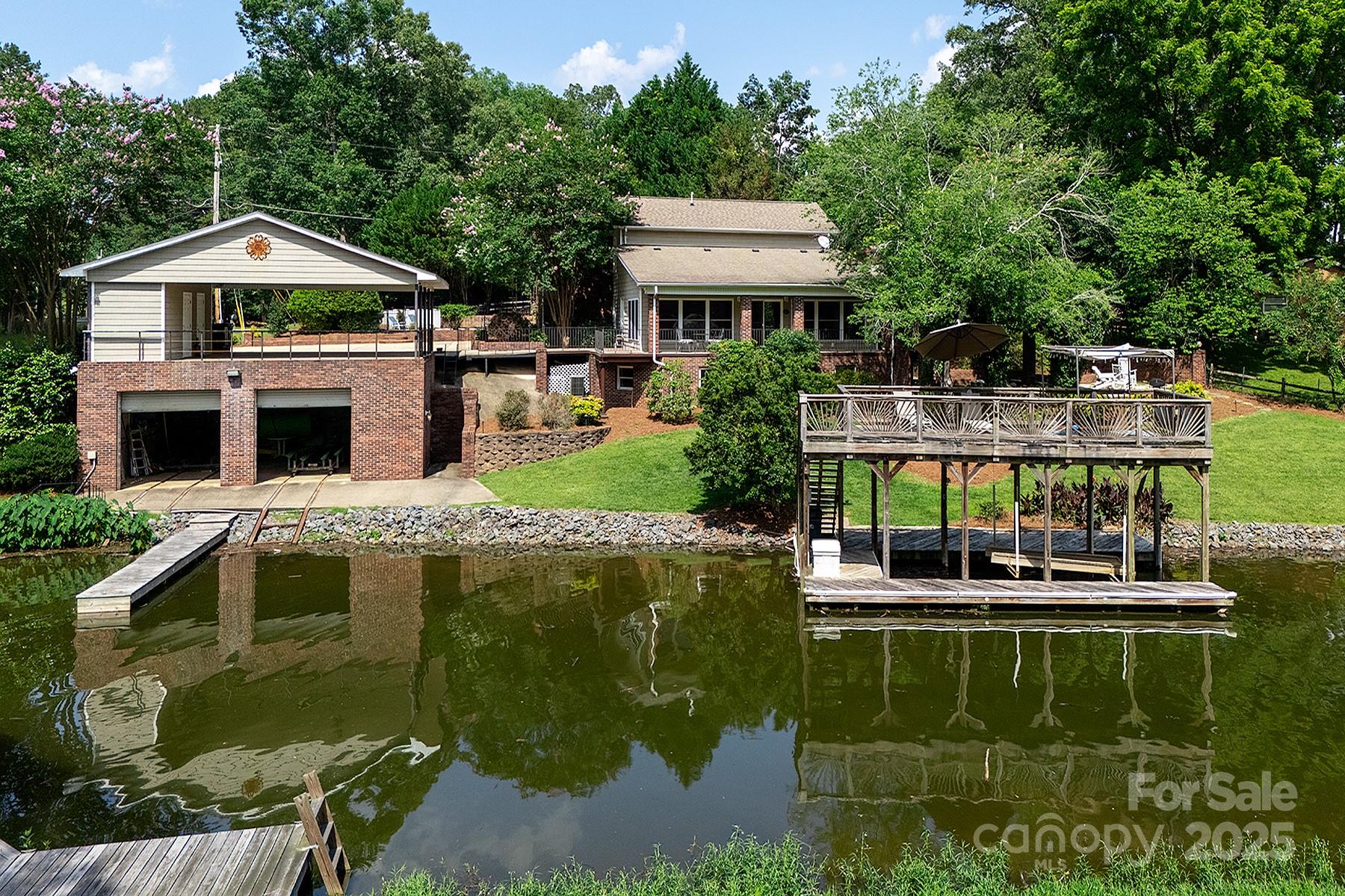 Just off the main channel of Lake Tillery, this private custom retreat is designed for the ultimate lakefront lifestyle. With over 4,000 sq. ft., the home offers spacious comfort for both entertaining and relaxing. Primary suites on the main and upper levels make it ideal for hosting or vacationing. Enjoy terraced outdoor living, an in-ground pool, and approximately 200 ft. of shoreline. Two wood docks with lifts and a 950 sq. ft. enclosed boathouse—complete with roll-up doors and electric self-recovery—offer easy lake access and secure storage for watercraft. From the dock, take in serene views of the James B. Garrison Bridge. Whether you’re cooling off in the lake, lounging by the pool, or cozying up by the fireplace, this home delivers privacy, comfort, and year-round enjoyment. No HOA. Short-term rentals allowed. Furniture negotiable separately. Whether you’re seeking a permanent residence or a weekend escape, you’ll fall in love with everything this lakefront retreat offers!