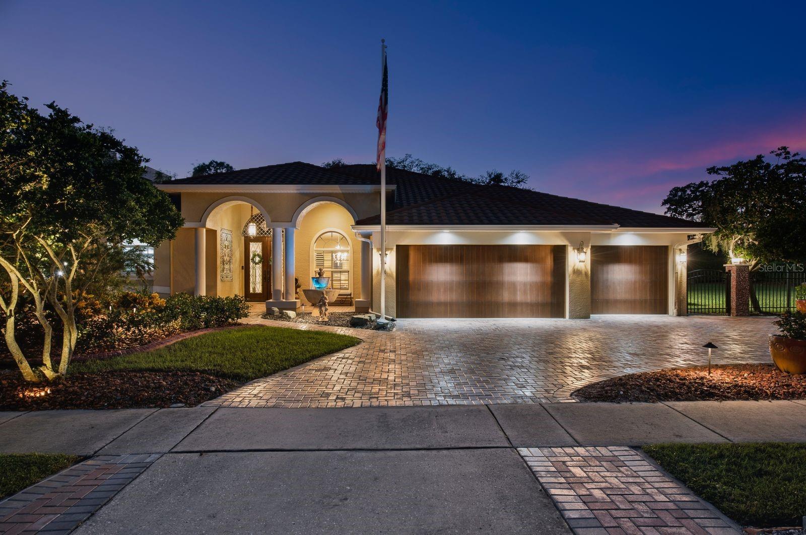 This one-of-a-kind sanctuary in historic Tarpon Springs offers a flawless blend of versatility and unmatched outdoor living. Situated within a vibrant golf cart community, the fully fenced 0.74-acre lot features lush landscaping and a beautifully pavered driveway leading to over 3,000 square feet of interior space. High ceilings and an open floor plan enhance the airy, spacious atmosphere, beginning with a warm foyer and formal dining area that open to a grand living room overlooking the pool. The heart of the home is the kitchen equipped with 42-inch wood cabinetry, granite countertops, and stainless steel appliances, seamlessly connected to a cozy den ideal for movie nights or a quiet home office. Designed with privacy in mind, the TRIPLE-SPLIT floorplan provides distinct living quarters for family and guests alike. The primary suite features rich Brazilian Tigerwood flooring, a large walk-in closet, and a spa-like en-suite bath complete with dual vanities, a garden tub, and a separate walk-in shower. Two comfortable guest bedrooms share a tucked-away full bath, while a third bedroom suite at the rear of the home offers direct patio access—making it an ideal setup for an in-law suite or visitor haven. Significant mechanical and structural upgrades add modern peace of mind, including a custom 2018 tile-look metal roof, a whole-house generator, a newer HVAC system, a central vacuum, a built-in sound system, and updated lighting and fans. The crown jewel of this estate is its extraordinary RESORT-STYLE OUTDOOR LIVING SPACE. Screened for year-round comfort, the backyard paradise showcases a PebbleTec pool with a  waterfall and spa, fully controllable via smartphone app. The pool is equipped for a volleyball net. Entertain effortlessly in the covered lounge area, complete with overhead fans, TV mounting space, and an impressive outdoor kitchen outfitted with an Ignite grill and refrigerator, a Blaze cooktop, a Big Green Egg smoker, and a granite-topped fire table seating six. Beyond the screened enclosure, discover a serene garden area with pavered path leading to a sitting area within a private, fully fenced lawn. With current power existing to the rear sheds, the expansive yard offers vast potential to add an additional garage, guest casita, or ADU. LOCATED IN ZONE X, seller reports NO water intrusion!