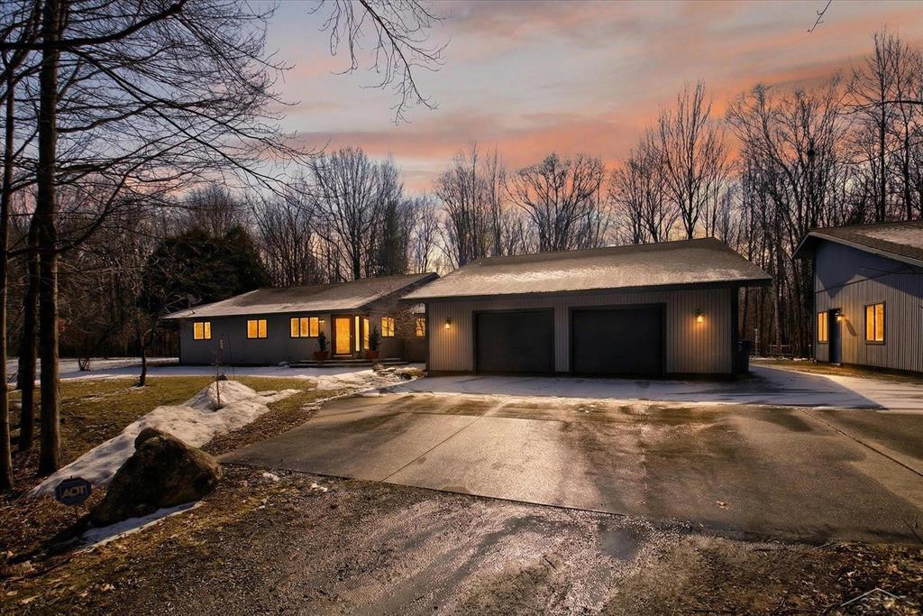 This stunning contemporary rambling ranch built in 1989 is perfectly designed for the entertainer or outdoor enthusiast, offering nearly 3,100 square feet of thoughtfully laid-out living space on a private 5.11-acre wooded parcel. Tucked away on a secluded private road, this home provides peaceful seclusion while embracing the natural surroundings with expansive windows and serene forest views throughout.  The open-concept main living area flows seamlessly, featuring vaulted ceilings in the great room that create an airy, inviting atmosphere ideal for gatherings. A natural fireplace (plumbed for gas) serves as a cozy focal point, perfect for year-round enjoyment.  There is a separate sitting area off one side of the living room, and a formal dining room off the other.  All three rooms are situated to embrace the love of the outdoors.  The massive kitchen is a chef's delight, boasting two ovens, two stovetops, abundant Corian counters, generous cabinetry, and plenty of room for multiple cooks while the layout opens directly to dining and living spaces for effortless entertaining.  A grandiose entry welcomes you with space for a large casual dining area, seating nook, or even a grand foyer table. The home includes 3+ bedrooms and 3.5 bathrooms, highlighted by the luxurious en suite master, featuring dual shower heads for spa-like relaxation.  Two other bedrooms are on the east wing of the home, while the versatile fourth bedroom (or bonus room) on the west side, offers an attached full bath, making it ideal for guests, and showcases beautiful oak paneled walls for added warmth and character.  Step into the enchanting four-season sunroom, a true highlight with its exposed wooden beams, tiled floors, and walls of windows framing peaceful wooded vistas-perfect for morning coffee, evening relaxation, or hosting year-round.  Outdoor enthusiasts will love the paver patio and decks that extend the living space into the private backyard. Additional features include lots of built-ins for storage and display, fresh paint thr