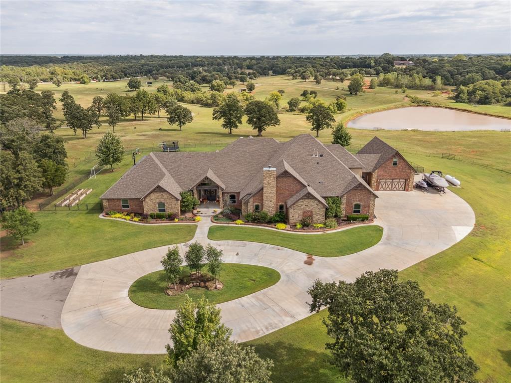 Experience refined luxury and self-sufficient living on this remarkable 10 acre private estate, thoughtfully designed with exceptional craftsmanship throughout. The stunning primary suite features a vaulted beam ceiling, hand-scraped walnut flooring, and a wood-burning fireplace with a cozy sitting area. The spa-inspired en-suite offers a walk-in shower with dual heads, a large soaking tub, and an oversized walk-in closet that also serves as an F5-rated safe room. Each secondary bedroom includes its own private bath and walk-in closet. The executive office showcases hand-scraped wood floors and custom built-ins. The gourmet kitchen is a chef’s dream, complete with two islands, farmhouse and prep sinks, two dishwashers, reverse osmosis system, South Bend 10-burner gas range with double ovens and broiler, custom vent hood, Sub-Zero refrigerator/freezer, and a walk-in pantry with custom wood accents. The spacious utility area includes dual washers and dryers, rolling island, sink, built-in storage, mudroom, and a secondary office space. Upstairs offers a game room, media room, and exercise room. A climate-controlled dog room with automatic door and wash station adds convenience. Additional features include a grand vaulted entry, formal living room, motorized shades, plantation shutters, smart thermostat, spray foam insulation, private sauna, and a full security system with 8-zone cameras. Outdoors, enjoy a 35,000-gallon heated saltwater pool with tanning ledge, diving board, slide, and 10-person hot tub. A 20x40 sports court includes three basketball goals, pickleball and volleyball lines, plus LED lighting. Equestrian amenities include an 8-stall horse barn with tack room, wash rack, and roll-up doors, along with six pastures and three paddocks with water. The property also features four water wells, a large pond, Rain Bird sprinkler system, and two rental homes—ideal for guests or income potential. This estate perfectly blends luxury, comfort, and functionality.