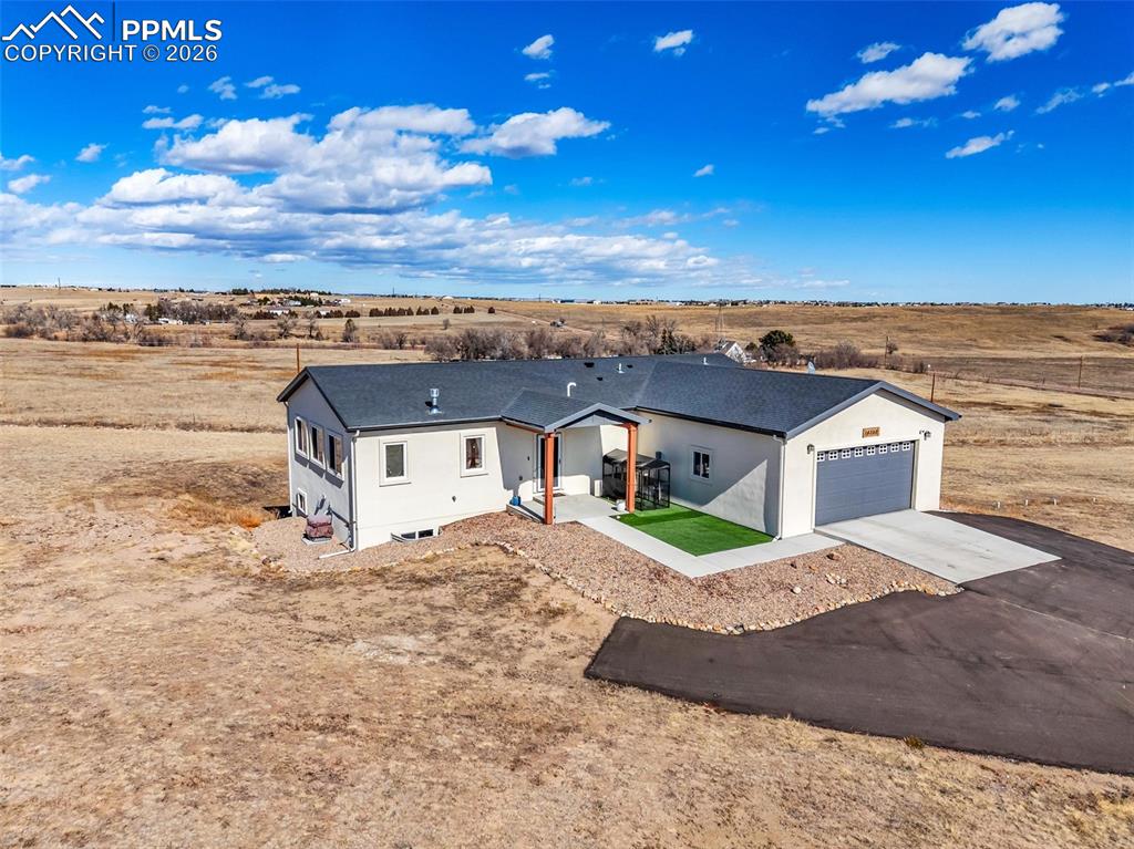 Trade crowded neighborhoods for open skies and room to roam with this beautiful 3,360 sq ft, 4-bedroom, 3-bath ranch-style home on 5 tranquil acres just outside the city. Inside, rustic comfort meets modern rhythm under vaulted ceilings and luxury vinyl plank floors built for real life. The open main level revolves around a granite-topped kitchen and island—where stories are shared and meals begin—opening into a fireplace-warmed living room and out onto a walkout deck that turns ordinary mornings and ordinary evenings into small daily rituals.Down the hall, the primary suite is its own quiet escape, complete with a private deck and a spa-inspired five-piece bath—an easy place to reset at the end of the day. A second bedroom and full bathroom on the main level offer comfort and convenience.The fully finished walkout basement introduces a secondary living area with a wet bar & family room, offering a natural extension of the home for entertaining or unwinding. Two additional bedrooms and a full bathroom create versatile options for workspaces, studios, or multi-generational living.Built in 2023, this home delivers confidence in its major systems and roof, so you can focus on enjoying the lifestyle it offers. Outside, experience quieter days, darker night skies, and the escape from suburban sprawl—all while still being just a short drive from town conveniences. Zoned for horses and livestock, this property offers more than just space — it promises room for animals, wide-open views, and the timeless reward of owning your own slice of land.