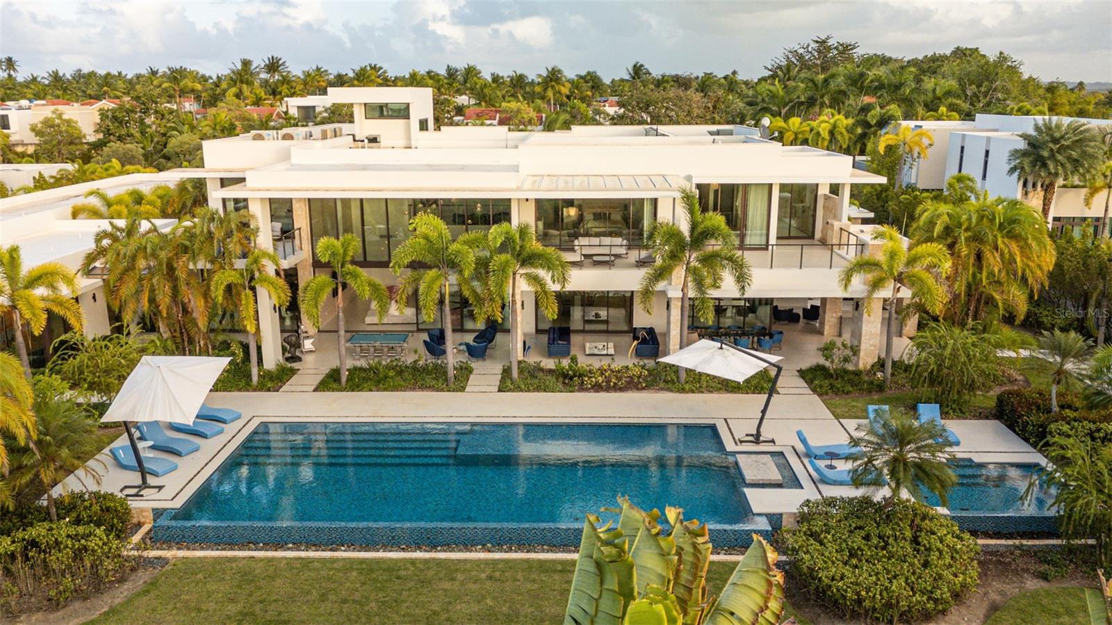 Situated within the prestigious Legacy neighborhood of Dorado Beach, this distinguished estate presents an exceptional blend of privacy, scale, and tailored luxury. Positioned on an expansive 4,800 square meter parcel, among the largest within the community, the residence enjoys a discreet setting along one of the resort’s most secluded streets.Offering approximately 16,746 square feet of total construction, the estate has been thoughtfully conceived to accommodate refined daily living as well as high-level entertaining. Bespoke amenities include a private two-lane bowling alley, a half basketball court, and a series of elegant indoor and outdoor gathering spaces. The exterior environment is anchored by a resort-style pool, a covered outdoor BBQ grill and kitchen, and a poolside dining area designed for seamless entertaining.The residence features three bedroom suites on the main level, each opening to private terraces, while the upper level is dedicated to two additional bedrooms and an expansive primary suite occupying its own wing. The primary retreat offers a generous private terrace, an oversized walk-in closet with center island, and a spa-inspired bathroom with an outdoor shower. A private office, an independent guest suite with its own entrance, and a dedicated salon space further elevate the home’s versatility and exclusivity.Architectural highlights include double-height ceilings, curated materials and finishes, a custom hand-blown chandelier, and fully integrated smart home and audio-visual systems. This is a rare and distinguished offering within Dorado Beach, delivering exceptional land value, custom amenities, and a lifestyle defined by understated elegance and modern luxury.