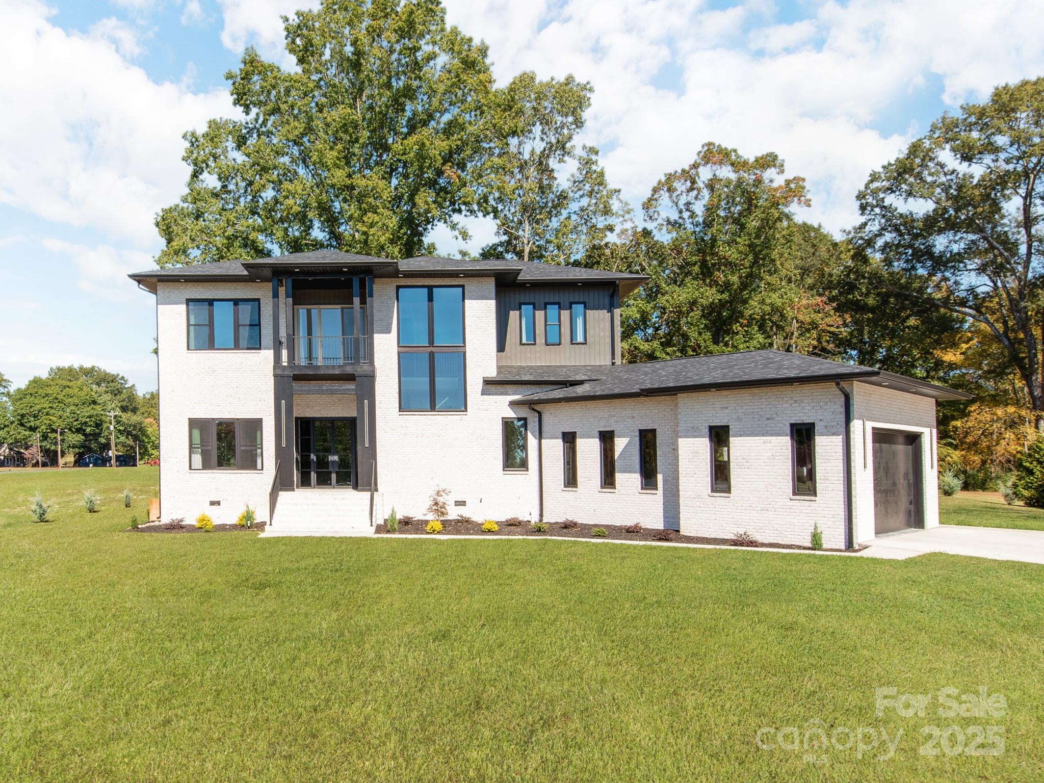 New Construction –2025 Build- Contemporary Elegance Meets Modern Functionality. Discover this stunning newly built contemporary brick home, designed with an open-concept floor plan and soaring 12'+ ceilings on the main level. From the moment you arrive, you’ll be captivated by the striking front entrance featuring modern glass double doors and a dramatic open staircase. Inside, expert craftsmanship shines through with custom woodwork, elegant lighting fixtures, and rich hardwood flooring throughout. Abundant windows fill the space with natural light, creating a warm and inviting atmosphere. The chef’s kitchen boasts a sleek L-shaped design with expansive counter space, a large center island, and oversized windows overlooking the outdoors. The kitchen seamlessly flows into the spacious family room and sophisticated dining area—ideal for entertaining or everyday living. Step out from the family room to a generous 360sqft covered rear porch, perfect for relaxing or hosting gatherings. Main-Level Retreat:Luxurious primary suite on the main floor features a spa-inspired bathroom with premium finishes—a true owners retreat. Large laundry/keeping room with a convenient half bath adds functionality to the main level. The oversized 759sqft garage is fully insulated, heated, and cooled—ideal for a workshop, gym, or additional flex space. Upper-Level Comfort:Three large bedrooms each offer large walk-in closets and private en-suite bathrooms. A versatile flex space opens to a 95sqft walk-out porch. 10' ceilings and hardwood floors continue throughout the upper level. Outdoor Features:Set on a large, level lot with a private backyard that backs up to a tree line—offering both beauty and privacy.*some virtually enhanced grass in backyard photo*Don't miss your opportunity to own this exceptional home! Schedule your private showing today.