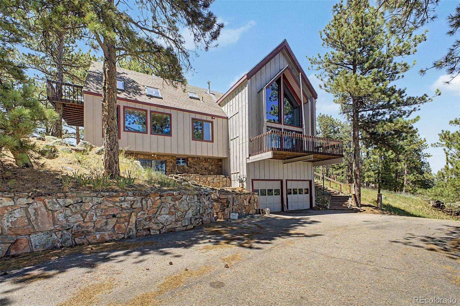 Welcome to 419 Wild horse. One of the premier lots atop Pine Brook Hill, sited on 3+ acres with over a full acre of flat, usable land — and among the rare properties in the neighborhood with commanding views in both directions: the Front Range to the east and the Continental Divide to the west. The existing home is built to capture it, with vaulted beamed ceilings, walls of glass, and multiple decks and flagstone patios opening into the pines. Bring your vision — an ideal candidate for a full remodel, or new build on one of the trophy lots in the neighborhood. Ten minutes to Pearl Street, yet completely secluded in a private mountain setting.
