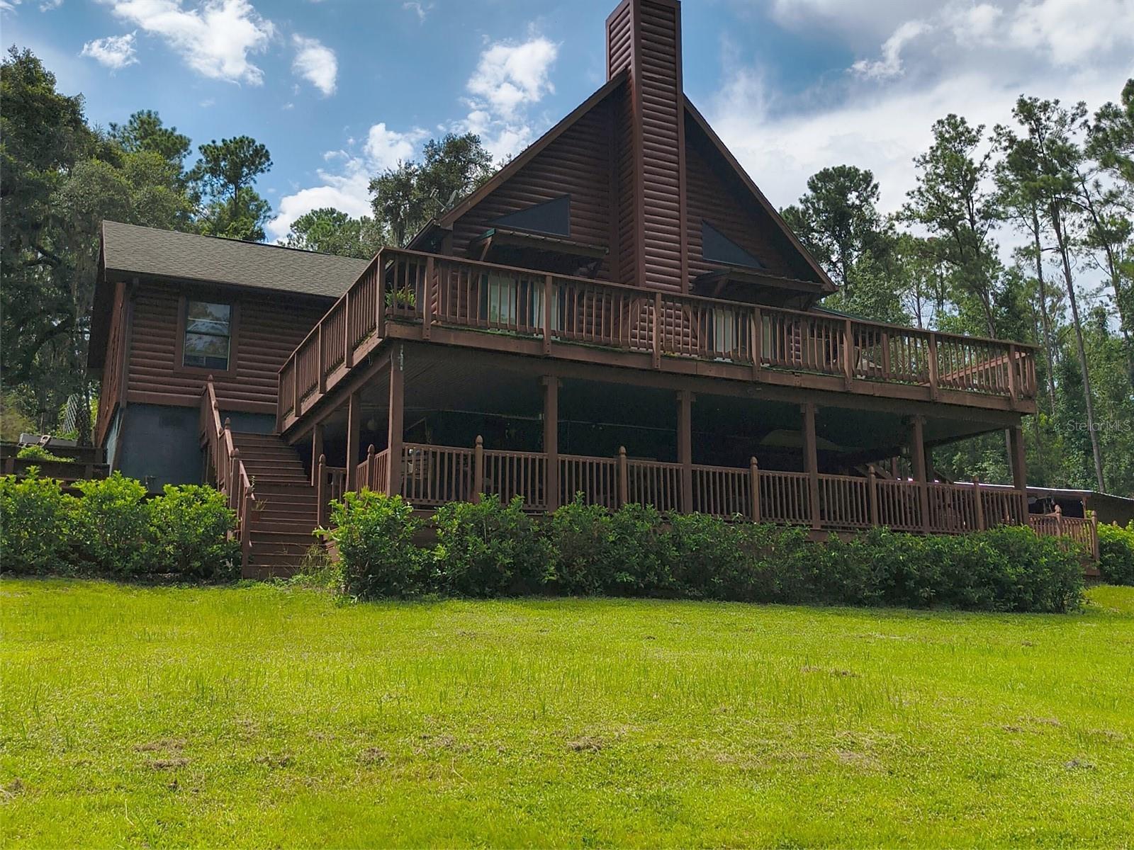 Welcome to paradise! Own your own nature preserve with a variety of trees, plants, and wildlife on this stunning 48-acre property. Drive down your majestic driveway over the spring-fed streams through a park-like setting to your log cabin style home sitting high on a hill. Main home consists of 1976 square feet, great room design, 3 bedrooms, 2 bathrooms, and tons of storage in an unfinished basement which is half underground. Living room, dining room, and kitchen have cathedral ceilings and tile floors. The walls are adorned with custom stone from floor to chair rail height to enhance rustic log cabin feel. There is a grand slate rock fireplace in the living room with custom railing separating the room from the massive kitchen. The kitchen is a chef's dream with granite countertops, a large island, gas stove with
additional grill top, and trash compactor. Enjoy time with family and friends on any one of the 3 decks attached to the home. There is a small
covered deck on the back overlooking a beautiful campfire circle. On the front of the home, there are 2 more decks, one covered and one elevated, large enough to host any sized gathering. The lower deck also has an outhouse styled bathroom, complete with running water.
Parking is never a problem when you have this much land. There is a 3-car carport, a carport cubby large enough for 2 golf carts, parking pad, space to store an RV with 30 amp electrical service, and ample room for a boat, towing trailers. A highlight of this property is "Boarshead Saloon".Just feet away from the main house is a 2-story building which houses a 580 square foot 1 bedroom apartment upstairs, with small kitchenette, living room, 2 half bathrooms, and loft. Downstairs, there is a 685 square foot old western style saloon, with bar, arcade games, living room area, and swim spa. Yes-you read that correctly. Enjoy swimming yearround, regardless of temperature and weather, in your very own indoor swim spa. You will love the endless relaxation with its many customizable jets, seats, color changing LED lights, and waterfall. Set the temperature of the water to whatever makes you feel most comfortable and end every day on a relaxing note. You can even watch TV from the swim spa if you wish. The "Saloon" comes fully furnished and decorated with the home. Most of the property is fenced and formerly housed goats and llamas. There are several fenced animal pens and shelters, to include a 24'x30' barn with water and electricity. There are several storage buildings situated on the property, to include a 13'x16' building with electricity, a 10'x20' shed with 2 lofts and attached 15'x20' enclosed on 3 sides covered barn, and a large 11'x28' log cabin style building with electricity and porch. Most of the 48 acres of property are wooded, with many trails cutting through the woods for walking, riding in a golfcart, horse back riding, or testing your skills on an ATV. You will find hundreds of tangerine trees amongst the towering pine and oak trees, along with 2 spring fed streams that meander through the property. Various pieces of furniture in main home and apartment can negotiated with price of home. A 2 person Kawasaki Mule with dump bed and zero turn Cub Cadet lawn mower are also available for a price or negotiation. Potential buyer(s) must provide current owners with proof of funds (either through pre-approval letter or bank account record) to cover list price of home prior to home/property showing
