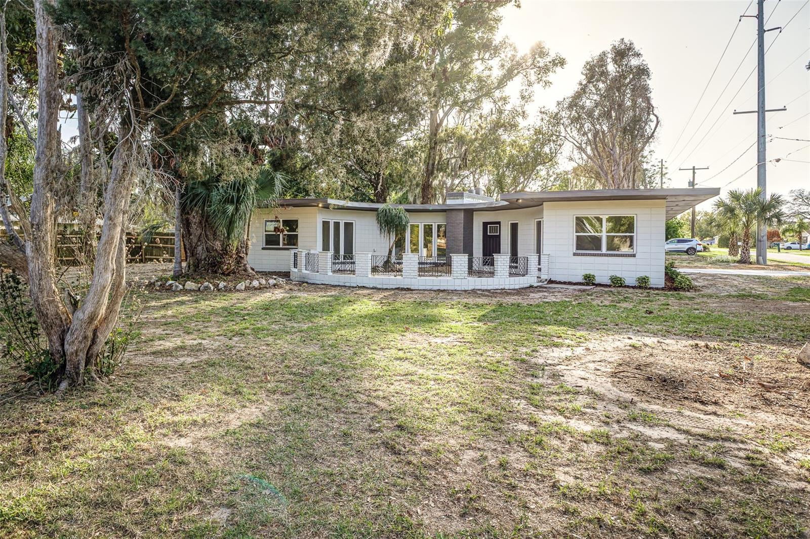 Step into something truly special with this one-of-a-kind semicircular home bursting with character and thoughtfully updated from top to bottom. Offering 3 bedrooms and 2 bathrooms, this unique property combines architectural charm with major upgrades, including new windows, a new roof, a new electric water heater, and a brand-new septic tank and drain field for peace of mind. Inside, you’ll find a fully renovated kitchen featuring stainless steel appliances, new cabinetry, and sleek quartz countertops, while both bathrooms have been tastefully updated and the home has been completely re-piped. The living space is warm and inviting, highlighted by a dramatic floor-to-ceiling wood-burning fireplace and expansive windows that flood the home with natural light. New luxury vinyl plank flooring flows throughout the main living areas, complemented by fresh carpet in the bedrooms for added comfort. A charming keyhole-shaped doorway adds a distinctive architectural touch as it connects the living space to the rest of the home. The interior laundry room is located just off the kitchen, conveniently close yet out of the way. Outside, enjoy a covered 225 sq ft side porch, a welcoming circular courtyard entry, a 2-car carport, and a detached 12x15 block workshop complete with electricity. Situated on a spacious .35-acre corner lot, this home is ideally located between Lake Alfred, Lake Cummings, and Lake Echo, and just moments from local favorite restaurants and everyday amenities. USDA FINANCING AVAILABLE FOR ELIGIBLE BUYERS, WITH NO MONEY DOWN. CALL TODAY FOR MORE DETAILS.