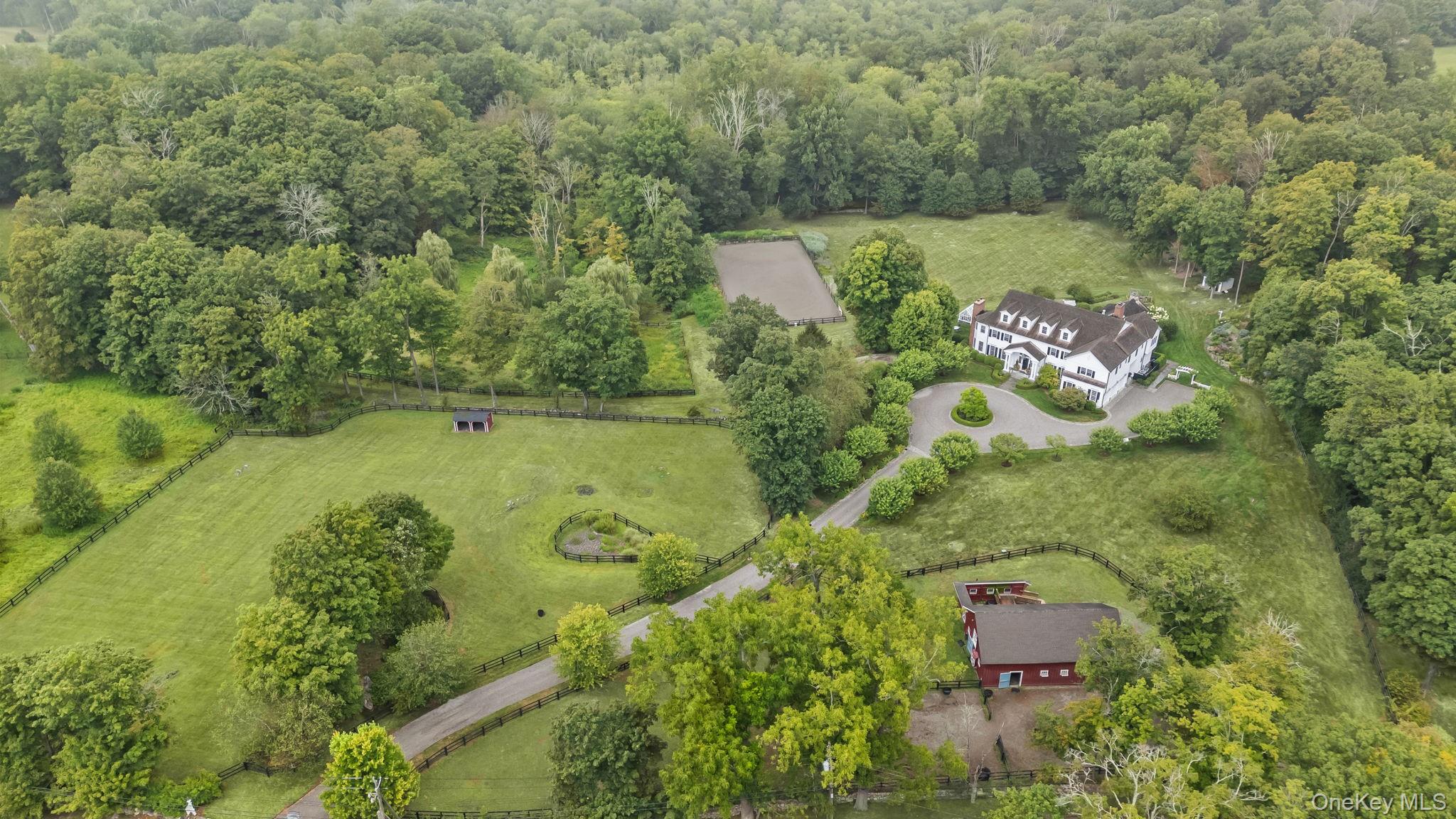 Olympic Hill Farm - A rare and remarkable estate nestled on 20 breathtaking acres in the heart of historic Guard Hill.  A gated Belgian block-lined drive leads to park-like grounds with mature trees, gardens, and sweeping lawns.  Every inch of this home reflects exceptional craftsmanship, from wide plank oak floors and coffered ceilings to elegant millwork and French doors.  The grand two-story foyer opens to formal living and dining rooms, a stunning library and fireplace, and a state-of-the-art Christopher Peacock kitchen featuring La Cornue, Wolf, Sub-Zero, and Miele appliances, plus marble and copper finishes.  Spacious family rooms on both levels, each with fireplaces, offer refined comfort.  The luxurious primary suite includes a fireplace, dressing room, spa bath, and Juliet balcony.  Five additional ensuite bedrooms (including one on the main level).  Lower level offers a custom wine cellar and tasting room w/fireplace, theater, golf simulator, and dog spa.  Equestrian facilities include an 8-stall stable with direct Bedford Riding Lane access, four paddocks, and an arena.  Outdoor highlights:  fireplace, patios, pergola, gardens, English greenhouse/potting shed, putting greens, and trails.  Prime location near trains, highways, schools, and dining.