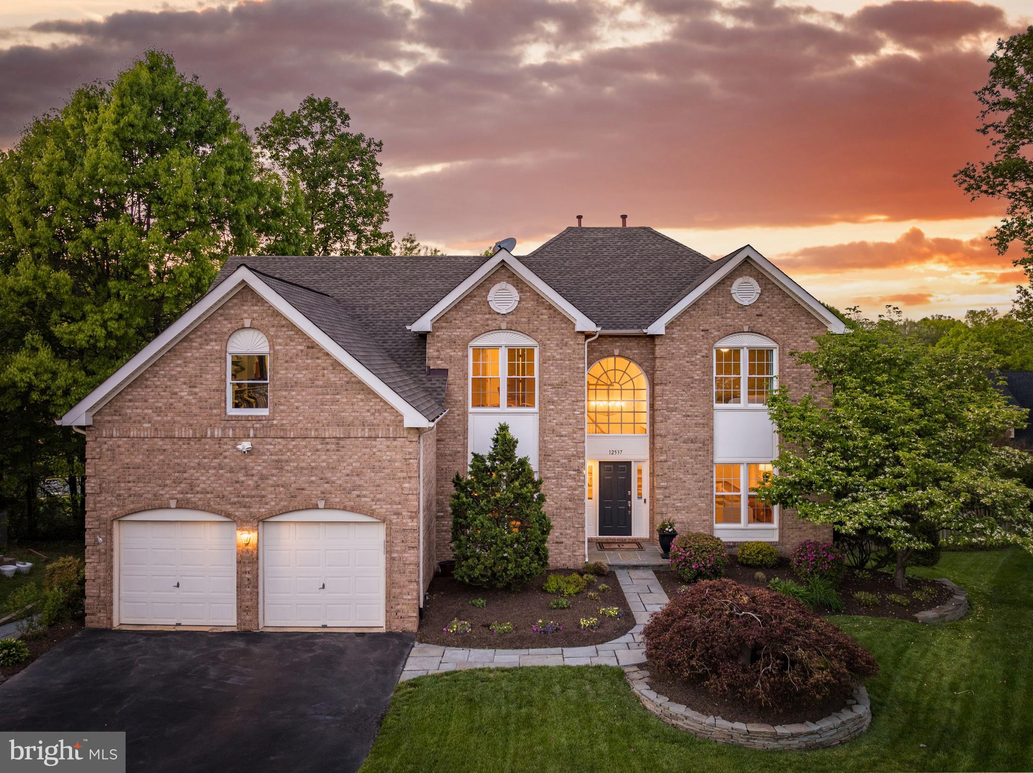 12537 Ridgegate Drive is the kind of home buyers hope to find and rarely do: a brick-front colonial with over 5,000 finished square feet on three levels, set at the end of a quiet cul-de-sac on an extremely private fenced lot with beautiful landscaping, room to play, and outdoor spaces that actually feel usable. From the moment you walk in, the home feels bright, warm, and generous, with sunlight pouring through the many windows and skylights, hardwood floors across the main level, recessed lighting throughout, and a layout that gives everyone space without losing the comfort of a true home. The main kitchen is designed for real daily living, with 42-inch white cabinetry, granite counters, stainless steel appliances, an island with seating, a walk-in pantry, wine fridge, and the kind of storage that keeps life organized. It opens to large gathering spaces, including a dramatic family room with soaring ceilings, skylights, and a gas fireplace, creating a central place to relax, host, watch the game, or spend a quiet night in. A main-level office with French doors and a full wall of custom built-ins gives you a proper work-from-home space, while the formal living and dining areas add flexibility for holidays, dinner parties, music rooms, homework zones, or whatever the next season of life requires. Upstairs, the primary suite feels like a true retreat, with hardwood floors, a spacious sitting area, a massive walk-in closet with custom built-ins, and a beautifully updated bath with heated floors, a towel warmer, custom marble counters, dual sinks, a frameless glass shower with multiple shower heads and a bench, soaring ceilings, skylight, and a private water closet. Three additional upper-level bedrooms are bright and comfortable with generous closets and ceiling fans, and the updated hall bath has the polished, timeless feel buyers want without needing to take on a project. Bedroom-level laundry adds everyday convenience, because no one wants to carry laundry up and down three levels if they do not have to. The walkout lower level is what makes this home especially flexible, offering a full bedroom, full bath, built-in bar or kitchen area, great entertaining space, and direct access to the rear stone patio. Whether you need space for guests, long-term family, an au pair, a private work area, a game room, or simply a second living zone, this level gives you options that most homes do not. Outside, the composite deck off the kitchen overlooks the private backyard, while the stone patio below creates another place to gather, grill, relax, or let the yard become the backdrop for everyday life. The oversized two-car garage, approximately 35 by 20 feet, offers incredible storage with ceiling storage on multiple walls, making it ideal for bikes, tools, sports gear, seasonal decor, and everything else that usually ends up without a home. The major updates are already handled, including roof and skylights in 2017, HVAC in 2016, water heater and sump pump in 2022, updated bathrooms, and an exterior gas line installed in 2025. The location is just as strong as the home itself, with easy access to downtown Herndon, Reston Town Center, Dulles International Airport, the W&OD Trail, Silver Line Metro stations, major commuter routes, hospitals, parks, trails, pools, golf, the Herndon Community Center, farmers market, concerts, restaurants, and all the daily conveniences that make this part of Northern Virginia so livable. Spacious, private, bright, flexible, and beautifully positioned, this is a home that gives buyers the room they need now and the options they will appreciate for years.