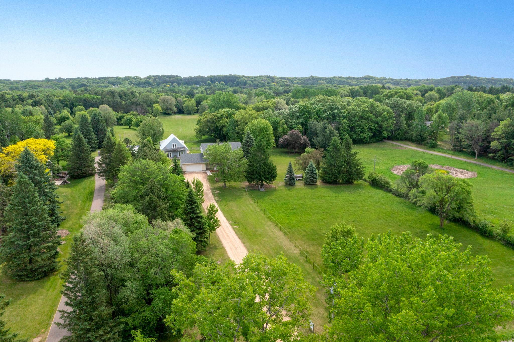 Welcome to this exceptional 4-bedroom, 3-bathroom home set on 5 private, fully fenced acres, offering the perfect balance of peaceful country living and convenient access to Highways 94 and 36, with shopping, dining, and everyday amenities just minutes away. The true standout of this property is the remarkable 1,540-square-foot heated and air-conditioned auxiliary building, offering endless possibilities for work, hobbies, recreation, or entertaining. Designed for year-round comfort, this versatile space features in-floor heat, split air conditioning, 10-foot ceilings, a half bath, a knotty pine gathering area, an upper-level flex space with balcony access, outdoor storage, and an attached hay loft. Whether you envision the ultimate workshop, home business, creative studio, fitness space, entertainment venue, guest retreat, or hobby headquarters, this one-of-a-kind building is ready to accommodate your lifestyle. For those with equestrian interests, the building also includes an additional barn area with two horse stalls featuring rubber mat flooring and a heated pasture water hydrant, making it ready for horses while maintaining incredible versatility for a variety of uses. Inside the home, you're welcomed by a tiled foyer with soaring 18-foot ceilings. The kitchen features new luxury plank flooring and black appliances (2025), abundant cabinetry, generous counter space, and both informal and formal dining areas. The inviting knotty pine four-season porch is warmed by a cozy gas stove and offers beautiful backyard views with direct access to the wraparound deck, creating the perfect space to relax or entertain. The main level also includes a bright living room, private office, laundry room, convenient half bath, and an attached two-car garage with backyard access. Upstairs you'll find three bedrooms, including a spacious primary suite with a walk-in closet and private bath featuring a jetted tub and walk-in shower. The renovated lower level (2022) expands the living space with a large family room, fourth bedroom, and abundant storage. Recent improvements include a new roof and seamless gutters (2022), fresh interior paint, updated light fixtures, and numerous thoughtful updates throughout. Whether you're looking for extra space to pursue your passions, run a business, entertain, or simply enjoy a unique property with unmatched flexibility, this one-of-a-kind home delivers comfort, functionality, and endless possibilities.