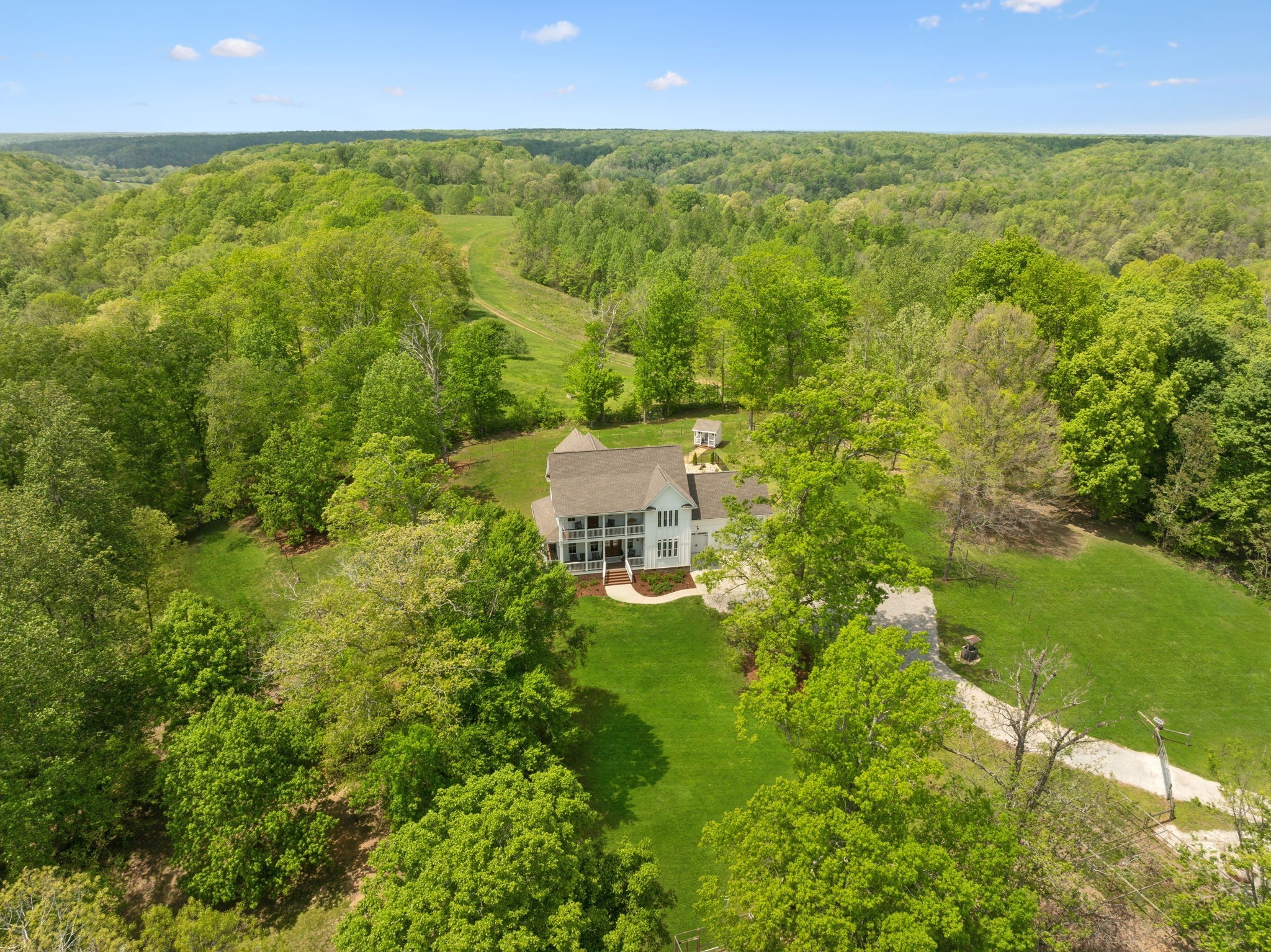 Experience unparalleled luxury and tranquility in this stunning 6,500 sq. ft. executive estate, set on 49 picturesque acres just minutes from Leipers Fork with the iconic Leipers Creek running through your own property! Designed for refined country living, this exquisite home features 4 spacious bedrooms, including a lavish main-level primary suite with an elegant ensuite bath and an oversized walk-in closet. Upstairs, three additional bedrooms including another master suite, a family room, and a private balcony offer breathtaking views of the rolling countryside.  Crafted for both relaxation and entertainment, the home boasts a custom wine cellar, a state-of-the-art theater, an executive office, and a workout room complete with an infrared sauna. Outdoors, enjoy a resort-style pool, lush grounds, and spectacular natural surroundings.  Equestrian enthusiasts will appreciate the 6-stall barn, insulated with the highest quality R19 insulation, and featuring a wash rack and a heated/air-conditioned tack room/office. The lighted riding arena, equipped with stadium lights, ensures optimal conditions for evening training. Scenic riding trails weave through the estate, offering a dream setting for horse lovers. A spring-fed, stocked pond enhances the property’s serene beauty. Nearly the entire property is fenced with a cross fence for horses as well as a yard fence for the guest house. Majority of the property fence is electric braid wrapped.  Additional living spaces include a charming A-frame guesthouse and a full apartment above the barn, providing 2,000 sq. ft. of combined accommodations—ideal for guests or extended family.  Perfectly situated 9 miles south of Leipers Fork and just an hour from Nashville, this estate offers both seclusion and convenience. A rare opportunity to own a luxurious countryside retreat, blending modern elegance with timeless equestrian charm.