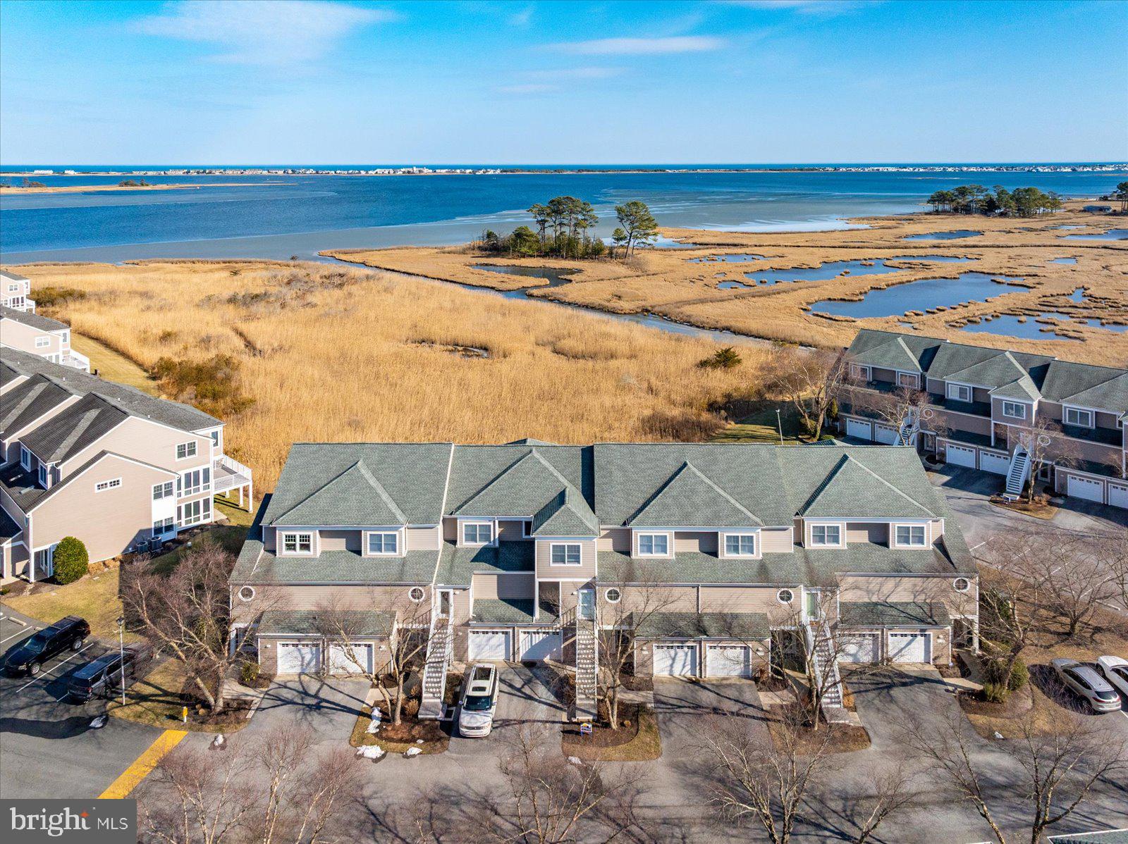 338312 Ocean Vista Drive #1082 in Selbyville, Delaware is a waterfront townhome in the desirable Bayville Shores community offering expansive views of the Little Assawoman Bay, surrounding wetlands, and the Fenwick Island skyline just minutes from the beach. This 3-bedroom, 3.5-bath residence features a light-filled open-concept main level with detailed trim work and a spacious granite island kitchen designed for entertaining and easy coastal living. Sliding doors lead to an open waterfront deck where you can enjoy peaceful morning sunrises over the bay, coastal breezes, and ever-changing natural scenery. The upper level offers a generously sized primary suite with a private deck overlooking the water—an ideal vantage point for sunrise skies—along with exceptional closet space rarely found in similar properties, while an additional en-suite bedroom provides comfort and privacy for guests. The entry-level suite opens to a covered patio and green space, creating flexibility for visitors, extended family, or a secondary living area. A conveniently located laundry area and attached garage with added storage enhance everyday functionality and beach-day convenience. Ownership is designed for ease, with the HOA covering exterior maintenance as well as flood and hazard insurance, while water service is included and the home is connected to public sewer. Residents also benefit from low electric rates through Delaware Electric Cooperative, and Bayville Shores incorporates community solar that has generated more than 1.5 million kilowatt hours of energy over time. Community amenities include a private boat ramp, kayak and paddleboard launch, pool, tennis courts, and scenic walking paths, all ideally located between the Freeman Arts Pavilion and the beaches of Fenwick Island. Short-term rentals are permitted, making this property equally attractive as a primary residence, second home, or strong coastal investment opportunity. Updates include a new hot water heater.
