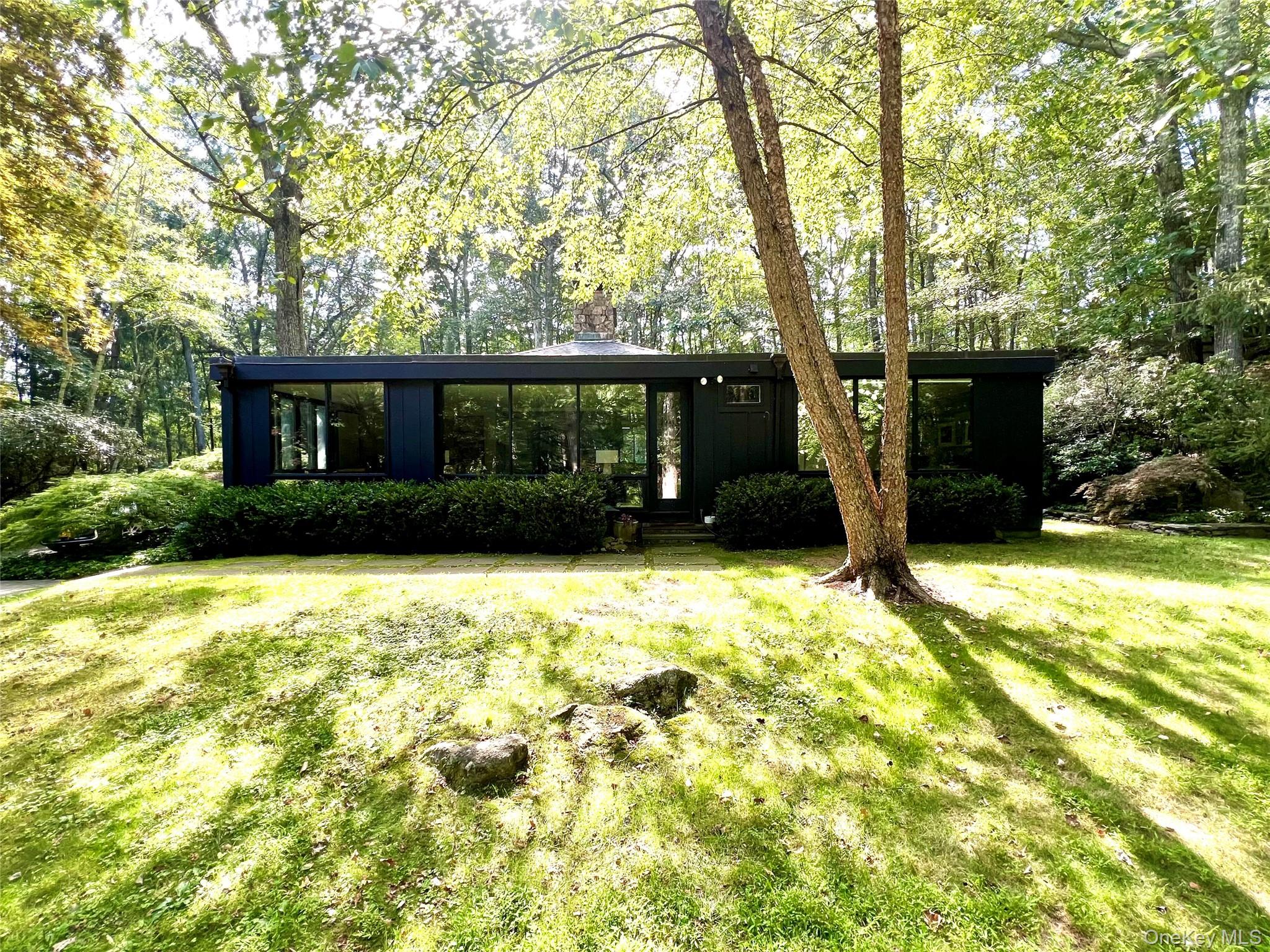Brookside. The perfect, private refuge. Long drive through woodlands to breathtaking grounds. Exceptional Modern surrounded by flowering trees and perennials, rolling lawns and dramatic rock outcroppings. Open and modern floorplan with a loft-like feel. Sun-filled spaces with high ceilings, walls of glass and skylights. Clean, modern aesthetic perfect for showcasing art and furnishings. Dramatic Foyer with floor-to-ceiling fireplace. Open Living Room and Dining Area. Chef’s Kitchen with custom cabinets, honed granite counters, two working islands and a breakfast area. Comfortable Den with skylight and window wall. Private Primary Suite with skylit Bath. Second Bedroom with ensuite Bath. Beautifully finished lower level with Family Room/Artist Studio/potential Bedroom. Private Swimming Pool overlooking a babbling brook. Peaceful setting yet easy drive to Scotts Corners, New Canaan, Metro-North trains and the Merritt Parkway. An incredible offering!
