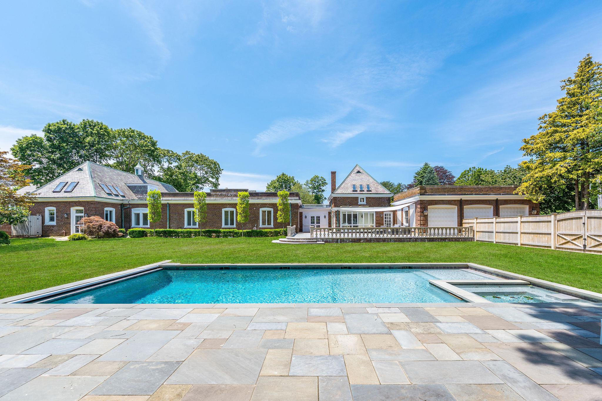 Welcome to one of the North Fork's most iconic and impeccably restored estates, where timeless grandeur blends seamlessly with refined modern living. Originally built circa 1915, this Georgian estate, formally known as the Cosden Estate, has been lovingly restored for today's modern luxuries while maintaining its historic vibe. Set on a professionally landscaped acre in one of Southold's most desirable locations, this 6,000sq ft home features 6 spacious bedrooms and 6 luxurious bathrooms. An entertainer's dream, this home includes a heated saltwater gunite pool with integrated spa, surrounded by a bluestone patio and enclosed by a classic Walpole fence with custom automated gate entry. Across the street, enjoy peace of mind and enduring views with 22 acres of unbuildable land. From the mature, symmetrical sugar maples at the front entrance to the elegant pleached elm at the rear, every inch of landscaping has been thoughtfully curated. Inside, soaring vaulted ceilings, herringbone wood floors, and a grand wood-burning fireplace define the stunning living room. Natural light pours in throughout the home, enhancing its warm, inviting atmosphere. The chef's kitchen, renovated in 2020 and refreshed in 2024, features new quartz countertops, a refinished oversized island, and custom open shelving. The primary suite offers a serene retreat with a spacious sitting room and a fully renovated spa-like bathroom with a soaking tub and a large enclosed shower. Additional highlights include, new HVAC system, upgraded ADT security system, State-of-the-art irrigation throughout, a large temperature-controlled wine cellar, and close proximity to Town Beach and Lighthouse Road Beach. The backyard is a private, quiet and peaceful oasis, perfect for relaxing or entertaining. This extraordinary estate offers a rare opportunity to own a piece of North Fork history, updated for today's lifestyle.