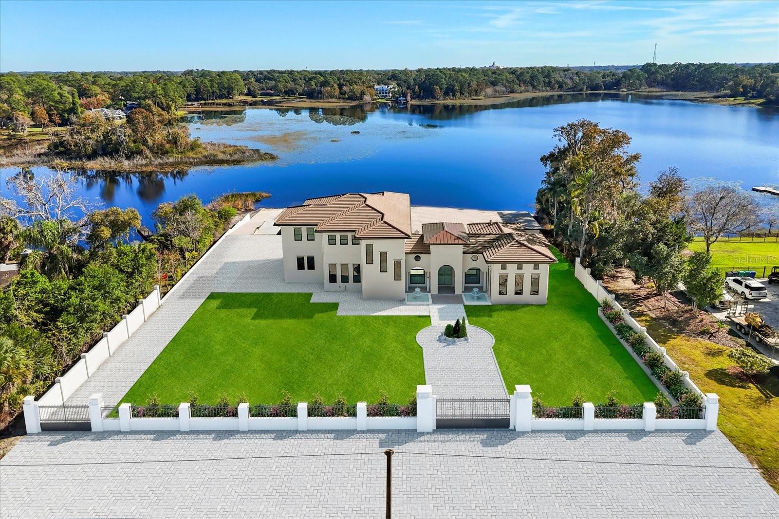 Under Construction. Expected completion Feb 2026. Welcome to an extraordinary lakefront opportunity on Little Lake Mary, one of Lake Mary’s most coveted private waterfront enclaves. This custom-built luxury estate spans approx. 7,000 sq ft and sits on over an acre of prime lakefront, offering expansive shoreline, unobstructed water views, a private boat ramp, and a lifestyle that blends privacy and sophistication. Opportunities of this caliber within the highly sought-after 32746 zip code are exceptionally rare.Designed as the seller’s forever dream home, the residence was thoughtfully planned and built with intention, legacy, and timeless luxury. As family needs have evolved, this creates a rare opportunity for a new owner to step into a home crafted without shortcuts or resale in mind. The home offers up to five bedrooms and four baths, including two primary suites—one on each level—ideal for multigenerational living or elevated guest accommodations, with elevator access between floors.The downstairs primary suite is a private retreat featuring a fireplace, luxury sauna, spa-style bathroom, and direct access to outdoor living areas, while the upstairs primary suite captures sweeping lake views and opens to a private balcony. Indoor and outdoor living flow effortlessly through a grand open-concept great room with soaring ceilings, expansive chef’s kitchen, and thoughtfully placed windows that fill the home with natural light while framing tranquil lake views.An oversized golf simulation room offers flexibility as a golf studio, media room, private lounge, or customized recreational space. Outdoors, the estate is anchored by a resort-style pool and elevated spa with dramatic water features and lake views, complemented by an expansive covered living area with outdoor kitchen, bar seating, multiple entertaining zones, and a dedicated fire pit lounge.A private gated entrance opens to a substantial driveway designed to accommodate multiple vehicles and gatherings. A large detached flex building offers versatility as a private gym, studio, home office, creative space, or potential in-law suite, while preserving the privacy of the main residence.The home is at an ideal stage of completion, offering the rare opportunity for buyer input on select final design elements including flooring, kitchen and bath countertops, select lighting, and front driveway and landscaping design—allowing personalization of a luxury lakefront estate without the extended timeline of starting from scratch.Ideally positioned in Lake Mary near top-rated schools, downtown dining, parks, and major corridors including I-4 and 417. Little Lake Mary is treasured for its calm mornings, stunning sunsets, and the rare feeling of being tucked away while remaining centrally located. Opportunities offering over an acre of lakefront with this level of craftsmanship and personalization potential almost never come available. This is more than a home—it is a legacy lakefront lifestyle.