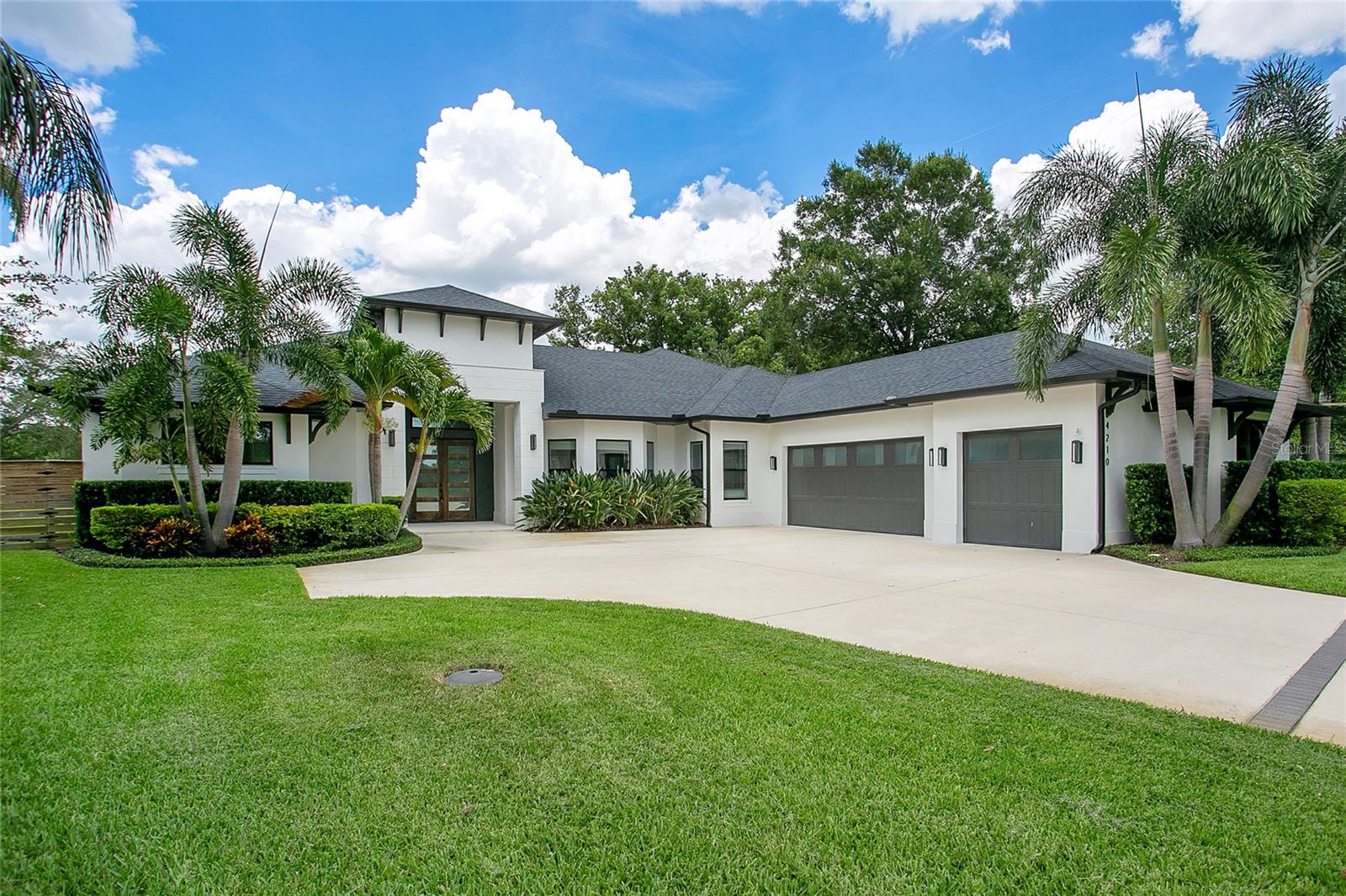 Some homes are built to stand out. Others are designed to settle you in. Here, you get both. Set on a quiet, dead-end street along the Conway Chain of Lakes, this custom-built saltwater pool home brings together architectural clarity, everyday ease, and a waterfront backdrop that never gets old. With 4 bedrooms, 4 full bathrooms, a 3-car garage, and a detached office, the layout feels expansive without overreaching — grounded by clean lines, volume where it counts, and private spaces that support real-life flow. The exterior sets the tone: modern but warm, framed by mature palms and a front entry that draws you in with intention. Inside, the foyer opens to a central living room — a quiet anchor at the heart of the home. From there, the layout unfolds toward the kitchen and family room, where pocket sliding doors disappear into the wall and the indoors spill effortlessly into the outdoor living space. The oversized island takes center stage, overlooking the family room and pool beyond — it’s where homework gets done, meals get made, and guests tend to linger. Just behind it, a hidden butler’s pantry keeps everything in its place — generous in size, functional by design, and tucked completely out of view. The bedrooms are each set in their own corner, offering privacy and flexibility. Two guest suites feature full private baths, while the third shares a nearby full bath. The primary suite spans the entire left wing — quietly set apart with a wall of windows, dual walk-in closets, direct pool access, and an ensuite that makes a statement without saying too much. A freestanding tub sits behind frameless glass, sharing space with a double shower and dual rainfall showerheads. Separate vanities and clean finishes keep the mood soft, balanced, and quietly luxurious. Even the laundry room gets it right — with custom cabinetry and a built-in dog wash that simply makes sense. But where this home truly settles into its identity is out back. Clean lines give way to open sky, water views, and a stretch of green that rolls gently to the lake’s edge. A saltwater pool and spa sit at the center, framed by a covered patio and geometric stepping pads — a space where conversations run long, the sunsets land softly, and the outside feels like part of the home. It’s quiet here. Intentional. The kind of yard that feels like a privilege to care for. Zoned for A-rated Pershing K-8 and Boone High School (Go Braves!). Tucked away, yet fully connected. Minutes to the airport, local shops and dining, and just a short ride to downtown — without ever feeling close to the noise. Everything about this home is exactly where it should be — in proportion, in placement, and in how it makes you feel when you walk through the door.
