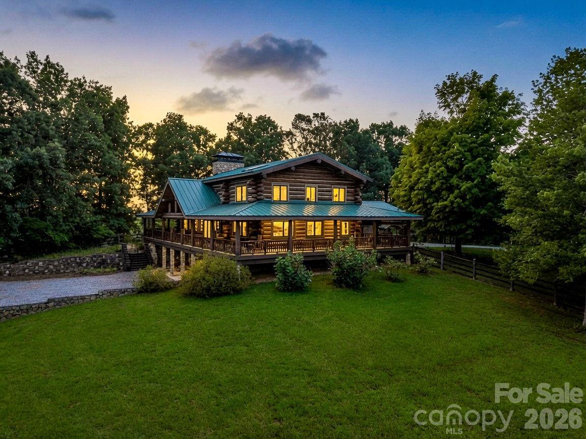 Rare and remarkable, this one-of-a-kind custom log estate is set on 34 private acres of some of the most spectacular land in Western North Carolina. Designed with the feel of a grand mountain lodge, the property offers an exceptionally rare combination of rolling pastures, sweeping long-range mountain views and complete privacy. The property's most spectacular building sites and panoramic viewpoints remain untouched, offering endless possibilities for a family compound, additional residences or simply preserving the land's natural beauty. Located just under 20 minutes from Lake Lure and only 15 minutes from the growing city of Rutherfordton, this remarkable property offers the perfect balance of privacy and convenience. Crafted from kiln-dried timber sourced from Nova Scotia and the Pacific Northwest, the residence reflects exceptional quality and timeless mountain design. Rich Brazilian and American cherry hardwood flooring, marble and ceramic tile, handcrafted mountain laurel picket railings and striking black polished South American granite featured on the exterior walls and steps showcase the home's remarkable attention to detail and enduring craftsmanship. The home features three en suite bedrooms, providing comfort and privacy for family and guests, while multiple flexible living spaces offer endless possibilities for home offices, guest suites, recreation rooms, fitness areas or creative studios. Although the home includes several additional rooms that could accommodate sleeping arrangements, the property is served by a four-bedroom septic permit. These expansive living spaces flow effortlessly onto approximately 1,700 square feet of wraparound decking and covered porches, offering countless places to relax, entertain and enjoy the changing seasons while taking in the breathtaking mountain views. Beyond the residence, the acreage continues to impress with rolling fields, wooded privacy and multiple premier homesites positioned to capture the property's incredible mountain views. Whether envisioned as a private mountain retreat, equestrian estate, family compound or future investment opportunity, the possibilities are extraordinary. A natural spring and an abundance of native wildlife further enhance the property's serene character, offering an authentic mountain setting that is as peaceful as it is beautiful.