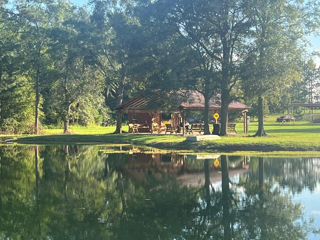 Gated & Fenced 12.86 acres with small stocked pond a Pavilion by the pond. This property has a half bathroom and additional room currently housing a refrigerator, sink and free standing stove for entertaining. A must see for the hunter that wants a small track of land to relax. Custom deer stand set up and ready for hunting season. Come out and see this property today. Seller has added an extra septic tank and a private deep well and is ready for a new build.