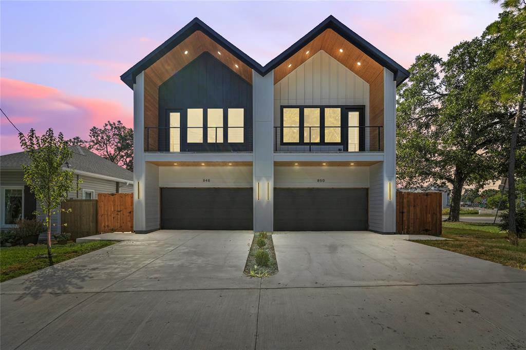 Modern home featuring a balcony, driveway, an attached garage, and board and batten siding