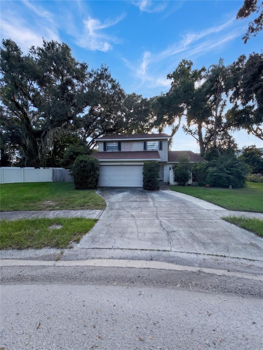 Welcome to 14714 Oak Vine Dr — a character-filled 4-bedroom home offering serene privacy in the heart of Lutz!  Enjoy exceptionally low HOA fees with access to community amenities such as a pool and clubhouse. Step inside to an open-concept main living space defined by soaring vaulted ceilings, a statement staircase, and an expansive second-story loft overhead. Abundant natural light floods through clerestory windows, highlighting the seamless transition between cozy living areas and modern wood-look flooring. Glass sliders lead directly into an impressive enclosed sunroom featuring authentic flagstone floors and wall-to-wall views of your peaceful backyard. At the push of a button, the entire home is protected by motorized, automatic roll-up storm shutters—delivering effortless, push-button hurricane protection and ultimate security in seconds. Located just minutes from top Hillsborough County schools, USF, I-275, and Tampa shopping. Schedule your tour today!