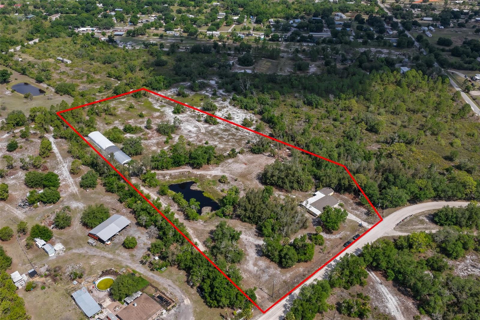 Discover the possibilities of country living, working from home and owning 7.25 acres of versatile agricultural property in Manatee County with a Wimauma address. This unique property features a 3-bedroom, 2-bath block home, a 6,000 square foot greenhouse/multi-purpose building, multiple wells, a natural spring-fed pond, a large workshop, and A (General Agriculture) zoning, offering an exceptional combination of land, infrastructure and flexibility for a variety of current and future uses. Immediate income potential exists for a buyer who chooses to continue the existing exotic tropical fish business. The versatile greenhouse and fully fenced acreage could also be adapted for a plant nursery, agricultural operation, storage for an automobile collection, hobby farm, horse property or space for growing fruit trees and vegetables. The possibilities are extensive and provide an opportunity to create a property tailored to your interests and goals. Located in an X flood zone, flood insurance is not required and there are no HOA or CDD fees. The home features an updated kitchen (2020), office/den, new roof (2022), leaf guard gutters (2025), new septic drain field and lift station (2020) and an inside laundry room with washer and dryer. French doors with blinds between the glass open to a large, newly screened lanai. Additional features include a covered outdoor storage area and an adjacent detached workshop/storage building. One of the property's most distinctive features is the 6,000 square foot greenhouse/multi-purpose building, consisting of a 2,000 square foot shop/storage area and a heated 4,000 square foot production area. The existing setup is well suited for aquaculture but could potentially be adapted for other agricultural, horticultural, nursery, storage or specialty uses. The acreage is supported by three wells. One deep well serves the home and includes a degasser, chlorinator and water softener. Two additional wells serve the greenhouse: a 50-foot shallow well providing acidic water and a 300-foot deep well providing hard/alkaline water. This existing water infrastructure is particularly well suited to aquaculture and other uses requiring different water characteristics. The greenhouse also includes six separate recirculation systems, six submersible pumps, an air compressor providing oxygen and aeration throughout the facility, floor drains for efficient maintenance and a Ryobi gasoline-powered backup generator to help maintain operations during power outages. A 2008 Yamaha gasoline-powered golf cart is included, making it easy to navigate the acreage and access the greenhouse. The natural spring-fed pond adds to the property's beauty and functionality. Whether your vision is to continue the existing aquaculture business, establish a new agricultural or specialty operation, create a hobby farm, develop a plant nursery, grow your own fruits and vegetables, keep horses or other permitted farm animals, store a vehicle collection or simply enjoy the space and privacy of 7.25 acres, this property offers a rare combination of land, improvements, and future possibilities. Call for additional details. Some home photos have been enhanced.