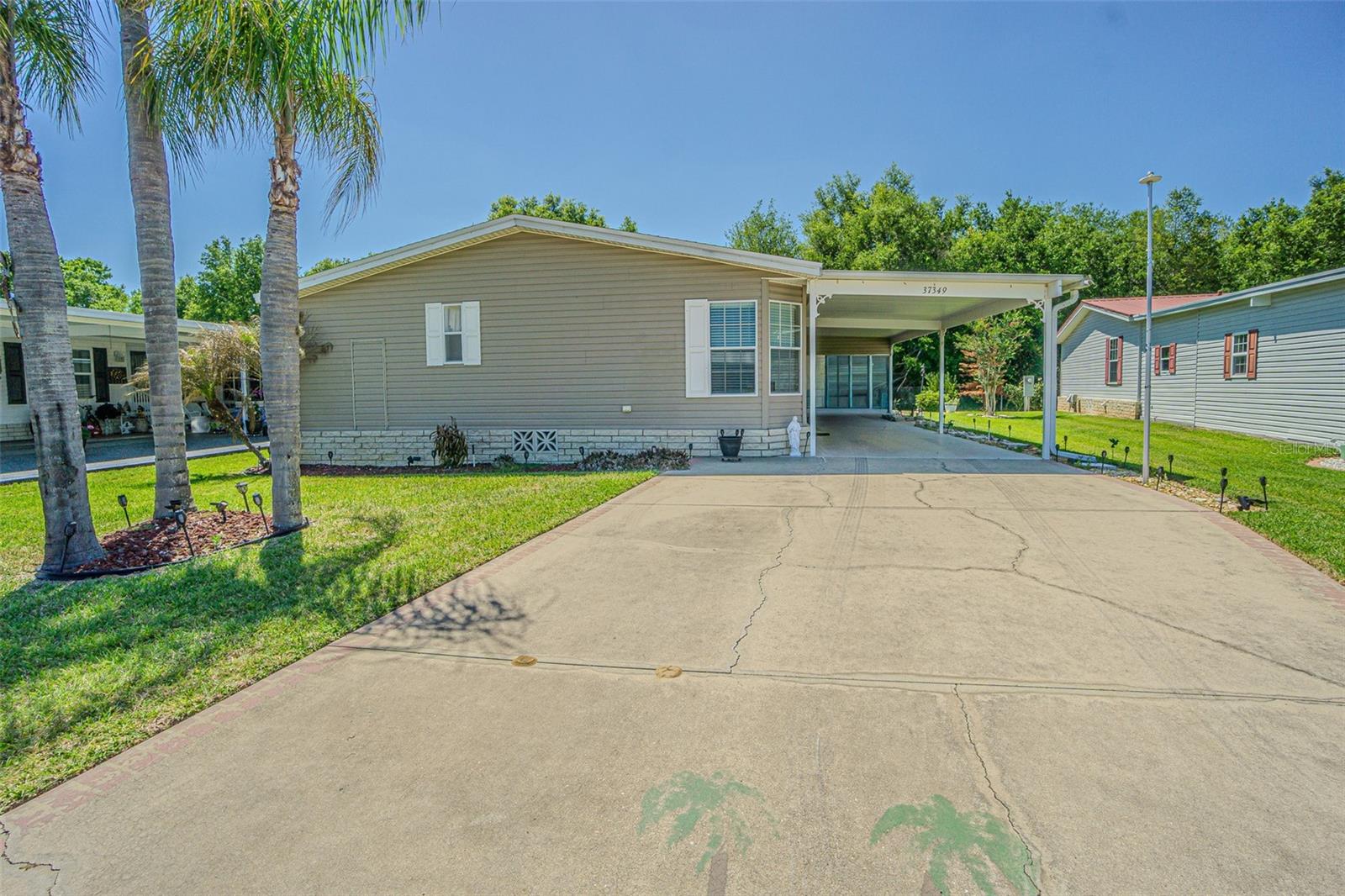 Welcome to Grand Horizons!  A Hidden Gem in the Rolling hills of East Pasco boasts balmy breezes, with an exceptional opportunity to enjoy the best of 55+ living in Zephyrhills!  NEW ROOF 2025, Newer AC 2024-25 on this beautifully maintained, 3 bedroom, 2 bath, Jacobsen home is nestled on a quiet cul-de-sac with no rear neighbors, offering both privacy and outstanding curb appeal. Lush lawn, meticulous landscaping, and a striking tropical palm—also etched into the widened driveway—create a memorable first impression. The covered two-car carport features ample space for vehicles, a sitting area and room to park your golf cart. This home features an enclosed Florida room with sliding windows, AC and a ceramic tile floor.  Don't miss the open rear patio in the backyard which invites you to grill, unwind, or soak up the Florida sunshine in your private oasis, complete with landscaped beds. Enter through the elegant oval leaded glass door into a ceramic tile foyer and immediately notice the craftsmanship throughout. Architectural details such as arched openings, etched glass accents, textured drywall, curved corners, and a soaring cathedral ceiling in the great room elevate the space. Double French doors lead to a versatile den or home office—ideal as a third bedroom—with a spacious closet. Luxury vinyl plank floors throughout the common areas adds to the appeal and updated feel. Thoughtfully designed split floor plan ensures privacy with the guest bedroom featuring a large window and an impressive walk-in closet, with a nearby full bath. The serene owner’s retreat is situated on the opposite end of the home and includes mirrored closet doors and a spacious ensuite bath with dual sinks, Corian countertops, an oval soaking tub, NEW stunning separate shower, raised cabinets and ample linen storage.  Light, Bright and inviting great room features a gable ceiling and triple window, filling the space with natural light. The open layout flows from the great room into the dining area and kitchen for easy entertaining. The kitchen is a standout with Corian counters, a breakfast bar with pendant lites, center island, generous cabinets, closet pantry and a newer Whirlpool Microwave & Smooth top range (2026) & Bosch dishwasher(2020). A well-appointed laundry room with Samsung washer and dryer, overhead cabinets, and additional storage adds convenience, with direct access to the enclosed sunroom. A large attached shed/workshop offers lots of storage with built-in shelves, a dedicated workbench and tool cabinet, pegboards and lighting. Enjoy the benefit of owning your land in this GATED, resident-owned community, where amenities include a heated pool, clubhouse with commercial kitchen, craft and billiards rooms, library, shuffleboard, and a full calendar of social activities for a low HOA fee. Ideally located north of Tampa near healthcare, shopping, dining, and major highways for easy access to Tampa, Lakeland, Orlando, and the Gulf Coast beaches.  Some furniture is negotiable... E Z Go 4 seater Golf Cart for sale.  CALL TODAY!