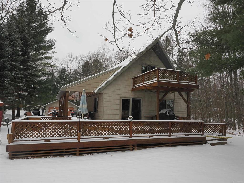 This excellent-condition Cedar Lake chalet offers a functional floor plan, a strong sense of privacy, and over 150 feet of east-facing lake frontage. The home sits on nearly 1.5 acres with approximately 157 feet of private shoreline.  Designed to maximize outdoor enjoyment, the property features a spacious yard, a covered south-facing porch, a large lakeside deck, and an upstairs balcony. The main level offers true single-floor living, with a bedroom, ADA-accessible bathroom, laundry room, dining room, living room, and kitchen all conveniently located on the ground floor. The dining room provides direct access to the expansive decking. Upstairs, there is a large space divided into two rooms, along with a half bath and access to the balcony. The home was completely rebuilt in 2005 and has been exceptionally well maintained since.  Cedar Lake spans approximately 1,075 acres and is relatively shallow, with much of the lake averaging around five feet deep and a maximum depth of about 12 feet. The lake is popular for bass fishing and has been intermittently stocked with walleye. This cabin is located south of the causeway, while most all-sport activity takes place north of it.  The property is just four miles from Oscoda, within biking distance of the beaches of Lake Huron, and directly across the road from Lakewood Shores Golf Course.