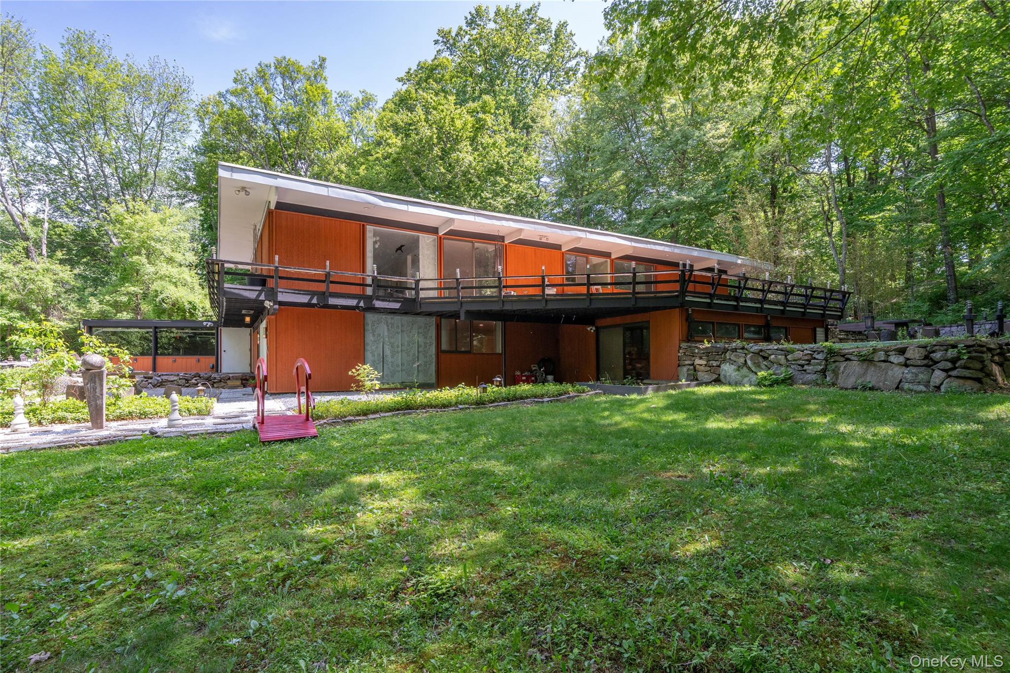 Tucked away on a quiet dead-end street in the highly regarded Byram Hills School District, this distinctive mid-century modern home offers privacy, style, and exceptional potential on over an acre of beautifully situated corner property. Thoughtfully designed with clean architectural lines, vaulted ceilings, oversized windows, and an abundance of natural light, the home blends timeless character with comfortable everyday living.The main level features a renovated kitchen with quartz countertops, breakfast bar seating, and easy flow to the living and dining area. Offering three bedrooms and three full baths, the home includes a spacious primary suite with en-suite bath and an impressive oversized walk-in closet. Outdoor living is a highlight with both a large wraparound deck and an expansive covered screened porch overlooking the private grounds.The full lower level offers tremendous additional space and flexibility, while the two-car garage adds everyday convenience. With central air and an unbeatable location just minutes to Armonk town, shopping, dining, and more, this is a rare opportunity to own a special home with enduring style in one of Westchester’s most desirable communities.