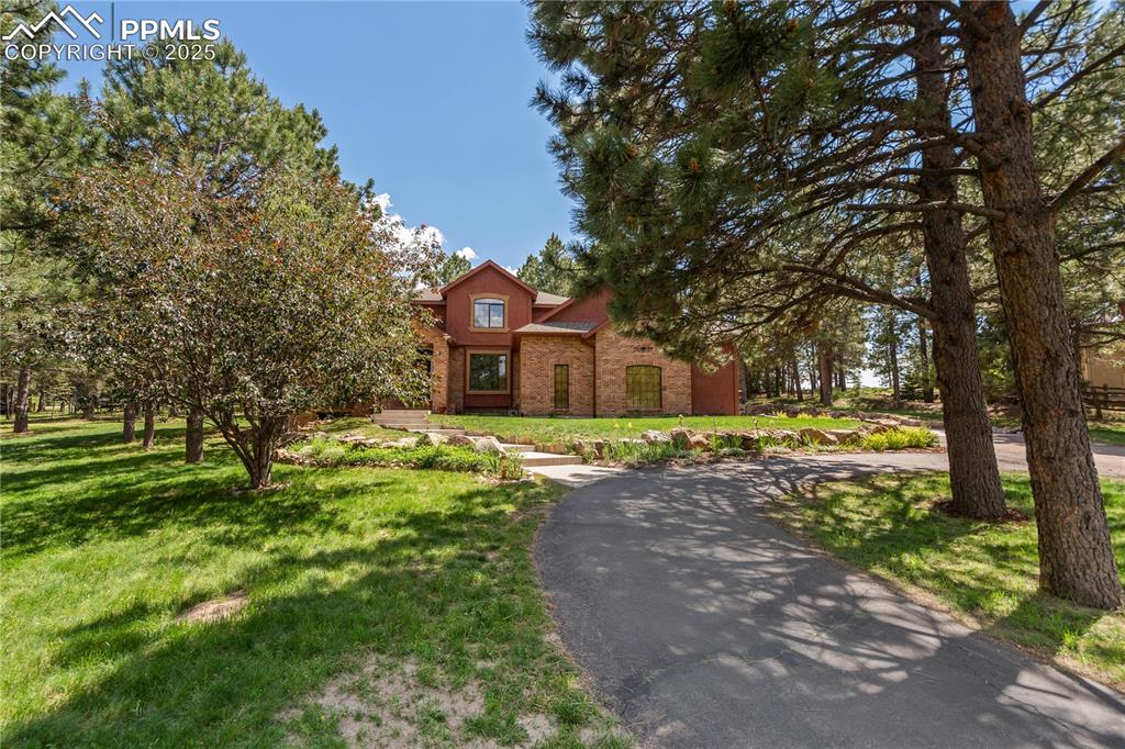 Nestled in the trees of sought-after Woodmoor, this 5-bed, 5-bath stucco home offers comfort, elegance, and thoughtful design throughout. The oversized 3-car garage includes RV parking, 2 large windows, and 5 ceiling-mounted bike racks. A circular paved driveway leads to the grand entrance, where you’re greeted by a stunning dual-entry staircase and freshly refinished hardwood floors.
The formal dining room features elegant wainscoting and dual access, including a pass-through to the kitchen. The front family room includes a cozy fireplace and views of the beautifully landscaped, flower-filled yard. At the rear of the home, the kitchen includes a gas range, stained-glass cabinet doors, built-in desk and china cabinet, wood pantry shelves, and a central island with a lighted pot rack. The adjoining informal dining area and living room flow to a ground-level oversized deck with a gas line and extra outlets—perfect for entertaining.
Off the main living area, you’ll find a private office and a spacious sunroom with a well-maintained hot tub. Upstairs, the large primary suite includes a sitting area, walk-in closet, and 5-piece bath with jetted corner tub and room for additional furniture. Three additional bedrooms and two full baths complete the upper level.
The finished basement features a bright family room with fireplace and 3 large windows, a 5th bedroom, full bath, hobby/storage room, and an open area ideal for a wet bar or reading nook.
Updates include: fresh interior paint, new carpet, refinished hardwood floors, a new furnace, and freshly stained deck. The yard is filled with mature trees, colorful flowers, and handcrafted sitting areas—offering a peaceful retreat just minutes from town.

This rare Woodmoor gem blends classic style, modern updates, and exceptional outdoor living. A must-see!