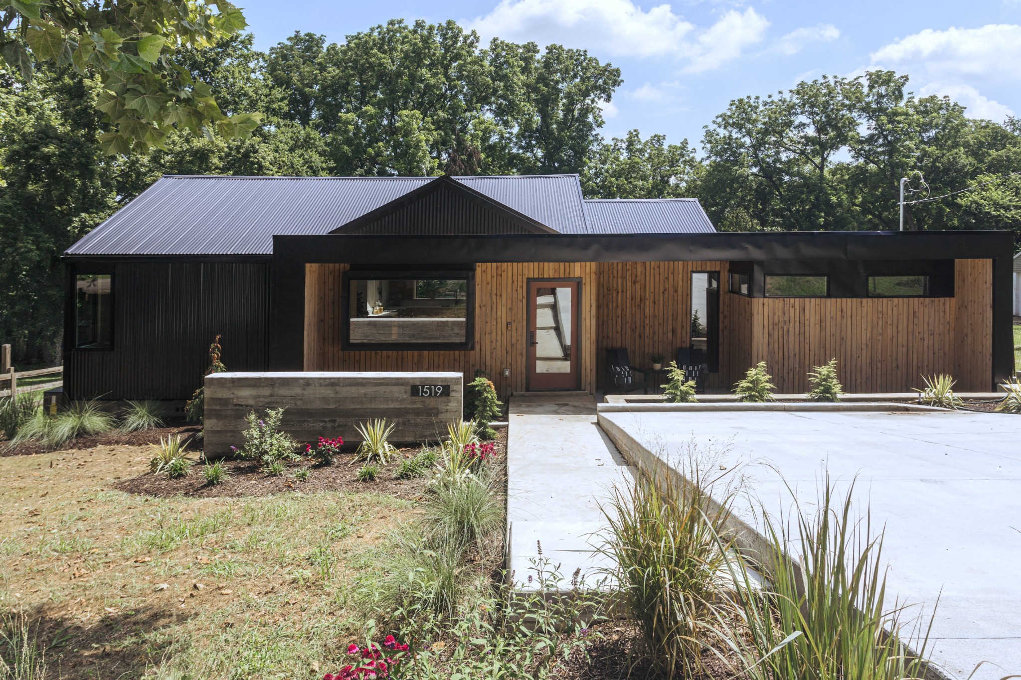 1519 Norvel Ave is a renovation study in blending modern architecture and material restraint, offering 4 bedrooms and 2.5 baths in the heart of East Nashville. Set back from the street with a bold mix of vertical cedar and black corrugated metal, the home makes a strong first impression—equal parts minimal and warm.

A poured concrete planter and clean-lined entry give way to a light-filled interior grounded by wide-plank white oak flooring and a quiet, neutral palette. Vaulted ceilings and thoughtfully placed skylights bring volume and softness to the main living space, where the kitchen acts as both anchor and showpiece. Custom white oak cabinetry, quartz countertops, a built-in banquette, and a slatted wood room divider strike a balance between function and architectural clarity.

The primary suite reveals exposed ceiling beams that match the oxide-painted doors—a rich, desaturated tone that recurs throughout the interior. A generous walk-in closet leads to the ensuite bath, complete with floating dual vanity, oversized format tile, and a glass dual walk-in shower framed by clerestory windows and light.

Three additional bedrooms are tucked thoughtfully throughout the floor plan, offering flexibility for guests, work, or play. Every finish was chosen for cohesion—matte black fixtures, solid wood millwork, minimal trim, and strong, clean lines throughout. A freshly poured driveway, integrated front and back patio, and curated landscaping round out the exterior.

A calm, architectural residence that offers space, light, and a sense of design discipline—just minutes from Shelby Park, Riverside Village, and all the best eats and hot spots in East Nashville.