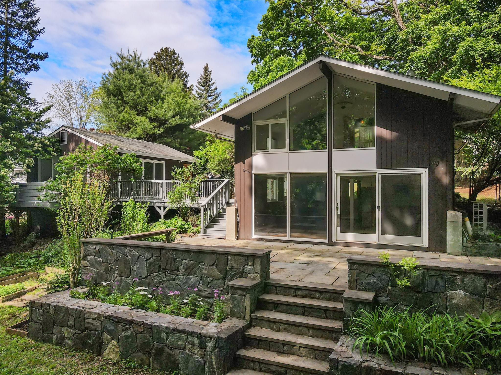 Trendy Mid-Century Modern style home with 400Sq Ft Bonus Studio in the desirable Village of Croton-On-Hudson. Charming 1,950s main house 3bedroom + home office, 2bath home with floor to ceiling windows, exposed brick accents, two fireplaces and vaulted ceiling in all bedrooms. Move right in with refinished wide-plank hardwood flooring, recently updated bathrooms with upgraded pluming and on-trend porcelain tiles, clawfoot bathtub and shower stall with glass shower door. Vintage Mid Century Entry door and lofted entry foyer. 2015 Renovated Kitchen with stone counters and seating peninsula. Enjoy ultimate flexibility of work-from-home and indoor-outdoor living with a bonus 400 Sq Ft studio just steps from main house front door. Fully set up for movie nights or entertaining and boasting oversized windows and glass sliding doors, heatpump HVAC and private deck. Large back yard bluestone patio just off the livingroom flows to tiered stone walls and a level back yard and raised garden beds.  Back yard access to woodsy town land with a stream and walking paths. 

In-Village and walk to town yet enjoy privacy, nature, woods all around all while on a quiet tree-lined street that dead-ends at Jane Lyttle Arboretum and Kaplans Pond. Croton Harmon Schools and Minutes to Croton Harmon MTA Train Station with Plentiful Parking and Sub 1 Hour Express Trains to Grand Central Station.