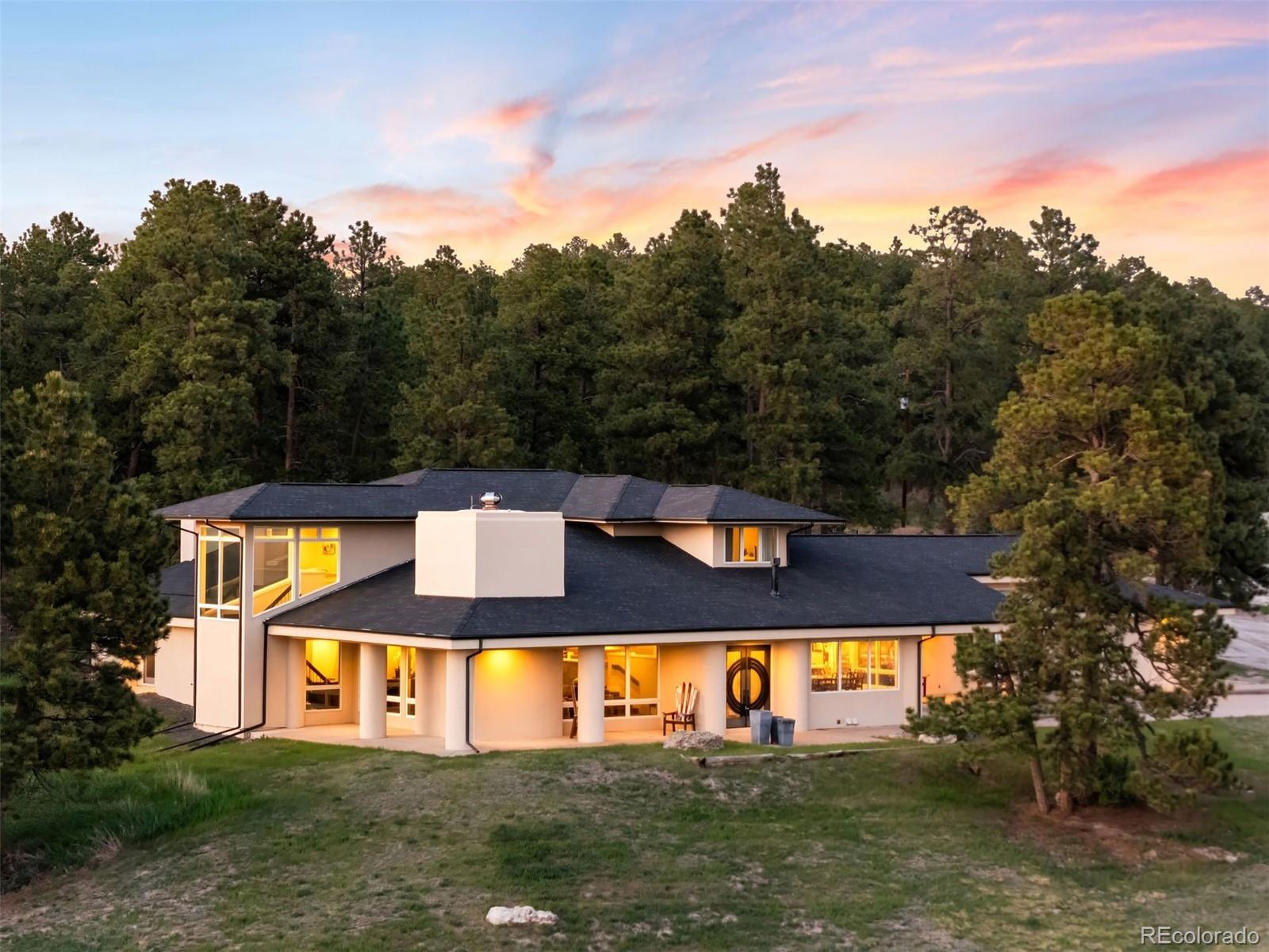 Most people go their whole lives searching for that ‘one thing.’ Out here, you just step outside and find it—157 acres of open sky, rolling pasture, and the majesty of Pikes Peak. Welcome to Discovery Farm, where life balances between peaceful retreat and fully functioning ranch. Two barns anchor the equestrian facilities, while guest houses, caretaker quarters, and utility buildings expand the possibilities for multigenerational living or retreat-style use, all tucked securely behind a gated entry. The main residence captures the essence of Colorado living, with mountain views that never grow old and comfort that becomes a way of life. 

Inside, the home blends mid-century character with modern refinement. Vaulted ceilings and walls of glass bring scale and light, while details like the open-riser staircase and wide-plank wood floors ground the space in warmth. The kitchen is a centerpiece, with a massive marble waterfall island and peninsula with breakfast bar seating, Wolf and Sub-Zero appliances, a bright windowed dining nook, and a separate scullery with commercial-grade refrigeration. The main-floor primary suite enjoys its own fireplace, a private patio, and spa-like bath with refined finishes. Upstairs, two ensuite bedrooms and a loft with built-in beds provide exceptional guest accommodations, while a main-floor den offers flexibility for work or retreat. 

The equestrian amenities elevate the property to professional standards, with two barns offering 20+ stalls, tack rooms, and wash bays, alongside an 11,000 sqft. indoor arena, utility building, and multiple sheds. An outdoor arena, trails, and fenced pastures stretch the landscape, supported by water rights that sustain pasture and livestock. 

Located 5 mins. from Elizabeth, 25 mins. from Castle Rock, and under an hour from DIA or Colorado Springs Airport, Discovery Farm delivers seclusion with ease of access. Paved roads bring you to the gate—beyond it, every sunrise and sunset is yours to claim!