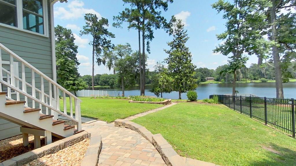 Welcome to this tranquil lakeside property featuring a meticulously maintained four-bedroom, three-bath home. The first floor offers three bedrooms and two full baths, including a spacious primary suite has been renovated with a luxurious tiled shower with double shower heads and a generous walk-in closet. The large living room boasts vaulted ceilings and seamlessly opens into a sunroom, offering stunning lake views. The recently renovated kitchen showcases hard surface countertops, a stylish tile backsplash, stainless steel appliances, a dedicated desk area, and a large bar with a wood grain top and extra cabinetry. The breakfast area also provides beautiful lake views, complemented by a pantry with pull-out drawers. All cabinetry throughout the home features soft-close hardware. The second ground floor includes a screened-in porch overlooking the lake, a separate living area, and a secondary primary bedroom with an en-suite bath, ideal for guests or family. Outdoor amenities enhance this exceptional property, including stone walkways, a gated and fenced yard, a greenhouse with a sink, lush landscaping, a stone fire pit, and a grilling stone patio. Additional features include a small boat launch and lake-fed irrigation to maintain the beautiful gardens. This home is perfect as a serene second residence, vacation retreat, or perfect primary home offering both comfort and stunning natural surroundings.