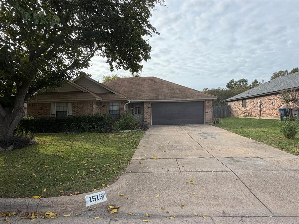 Single-story brick exterior featuring a hip roof, two-car garage, and concrete driveway