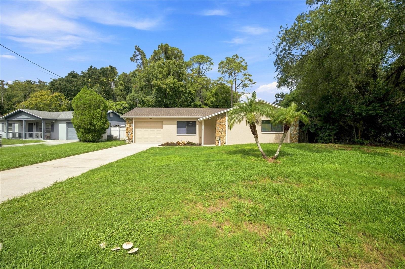 Enjoy comfortable single-story living in this inviting 2-bedroom, 2-bath home offering 1,303 square feet, an attached one-car garage, and a fenced backyard with a peaceful tree-lined view. Inside, the open living and dining areas provide a flexible layout filled with natural light, while the kitchen features abundant cabinet and counter space, a breakfast bar, and a full set of appliances. The spacious primary bedroom includes a walk-in closet and private bath, and the second bedroom is conveniently located near the guest bathroom. An enclosed rear patio offers additional space for relaxing, entertaining, or creating a versatile bonus area. Outside, the level yard provides plenty of usable space, complemented by a concrete patio, mature trees, rain gutters, and an extended driveway. Additional highlights include central air, ceiling fans throughout, an attached garage with laundry connections, no HOA, and a location in Flood Zone X. Conveniently situated near shopping, dining, recreation, and major roadways in New Port Richey.