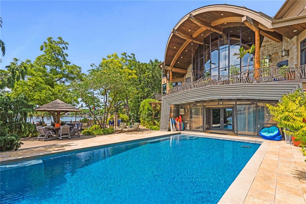 With an expansive lake front view, this home was designed for grand-scale entertaining yet tranquil retreat living.  A museum-worthy 1,000 bottle wine room and glass dome-topped, free-floating 3 story spiral staircase greet you upon entering custom front doors. Prepare to be wowed by a 26-foot barrel wood ceiling, extending thru the home, and 900-gallon living reef, saltwater aquarium. High-end finishes/fixtures throughout include natural stones, rare woods, Labradorite main kitchen countertops, and hand-blown glass Chihuly chandelier. Stunning architectural ceilings include one-of-a-kind dining room ceiling - truly a work of art. Private Primary Suite hallway with marble mosaic floor, beverage bar, and stairway to the library & gym/spa. Suite includes fireplace, home theater system, steam shower, and deck access. Telescoping enclosure enables year-round use of infinity-edge pool. Lovely al fresco deck-dining with outdoor kitchen, custom granite 22-person table, fireplace, TV, & lake views. Indoors connects to outside via LL bi-folding doors,  spa room and deck staircase. Lush, extensively landscaped grounds include gas torches, fountains, waterfalls, lighting, & integrated, computer-driven bug suppression system. Double boat dock with 4 hydro lifts. Appreciate the convenience & comfort of a 5 stop/2 door elevator, the latest smart home integrated system, 2 laundry rooms, dog shower, greenhouse, back-up generators, and heated driveway, steps, deck, main & lower-level European limestone floors. Midwestern-friendly, the Lake Winnebago community and well-stocked, 400-acre lake include many amenities. Why vacation at the lake when you can live the lifestyle every day? Home located less than 30 min from KC, in Lee's Summit school district.